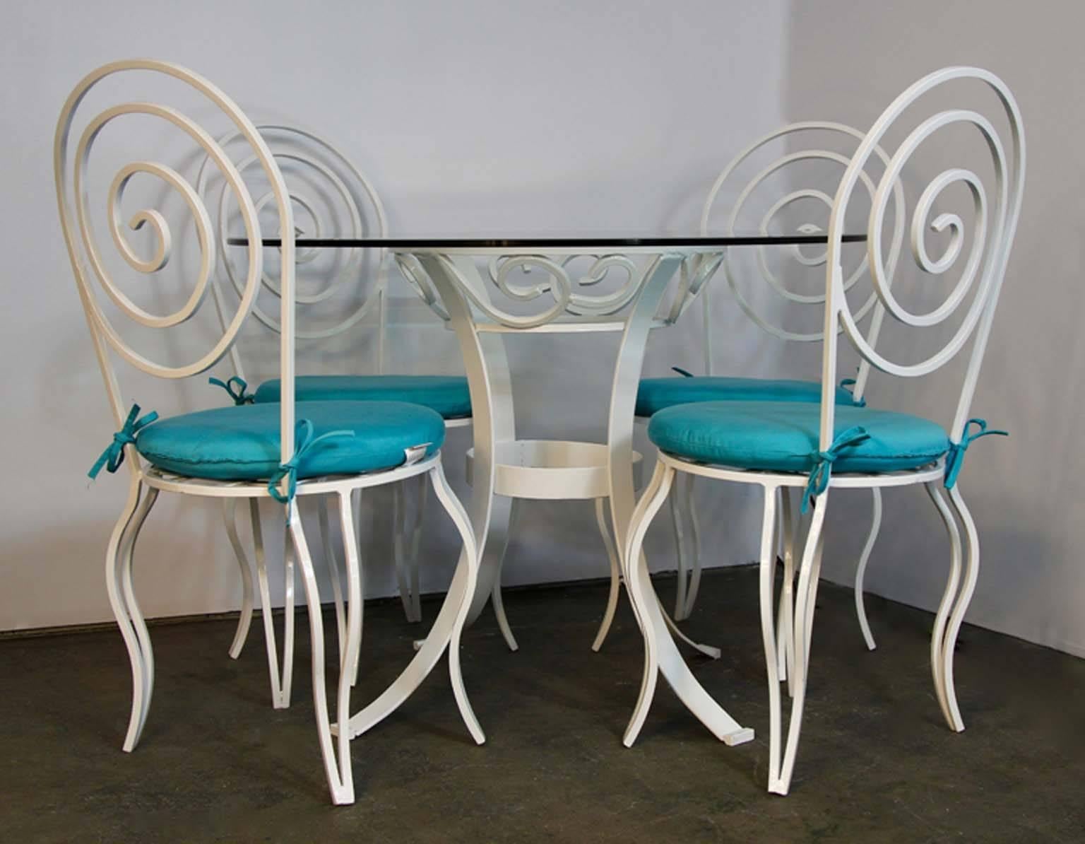 Hand-forged in a Brooklyn foundry in the 1920s. Sophisticated style for the times, featuring exquisite craftsmanship. The set included: Glass top table and four matching chairs with cushions. All items have been professionally sandblasted and powder