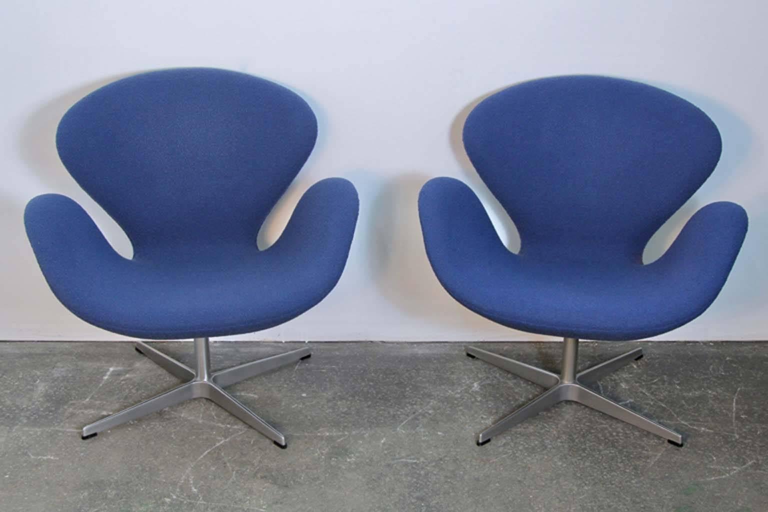 Pair of Arne Jacobsen swan chairs by Fritz Hansen, made in Denmark and distributed by Knoll Studio. Original blue fabric upholstery in good condition. One chair shows fading of fabric towards the lower back of chair on either side. Other chairs