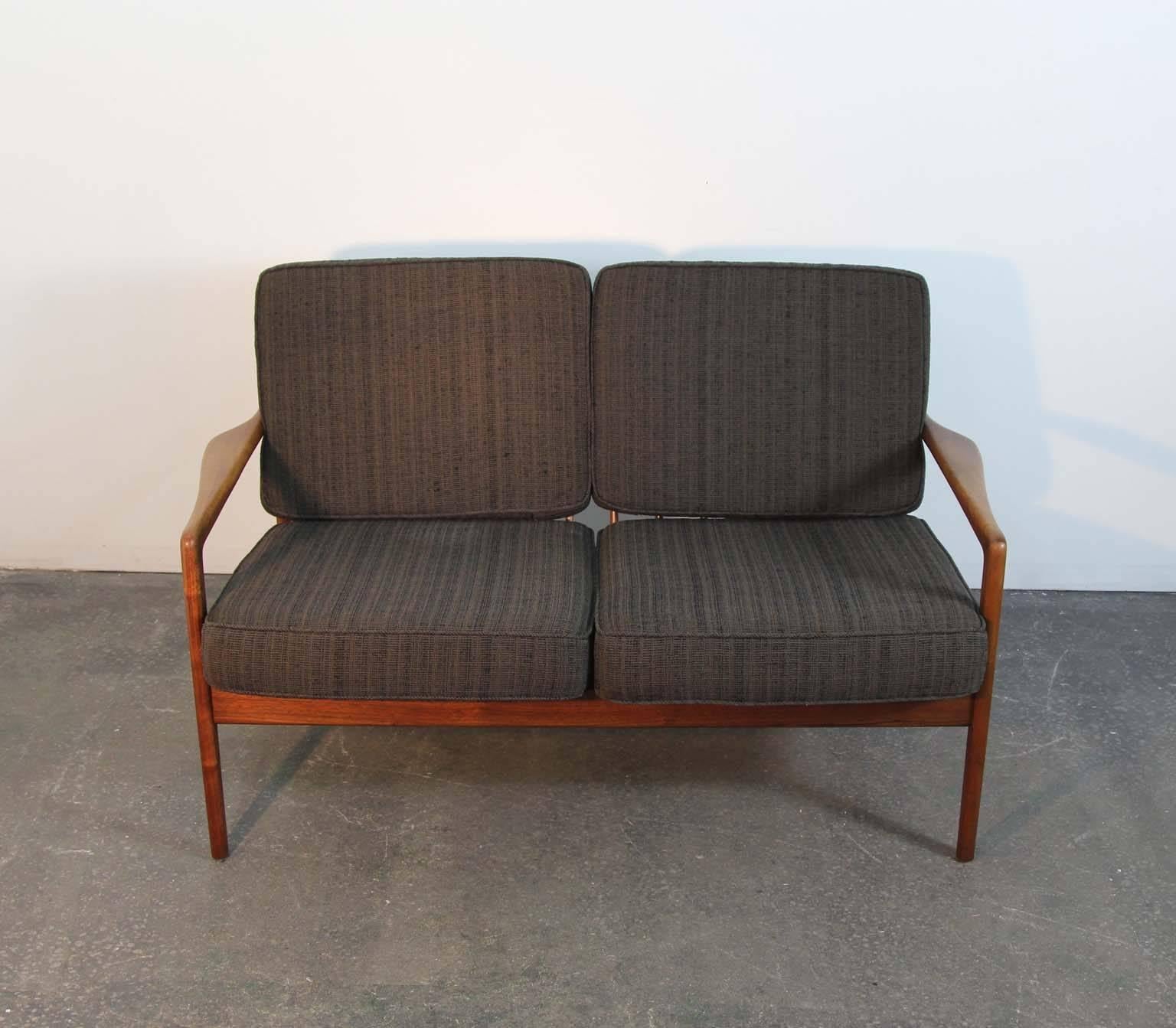 Two-seat settee and lounge chair by Folke Ohlsson for DUX. Teak frames have been treated to a re-oiling and are in good vintage condition with very minor marks from use. Sculptural joinery of frames are in excellent sturdy shape. New premium Pirelli