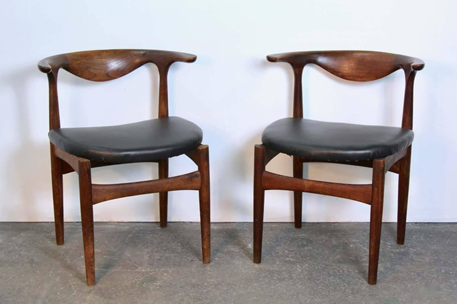 Pair of Scandinavian modern teak and leather chairs. Bullhorn style dining armchairs. Newly upholstered in black leather. One seat labeled Made in Denmark, no other markings.