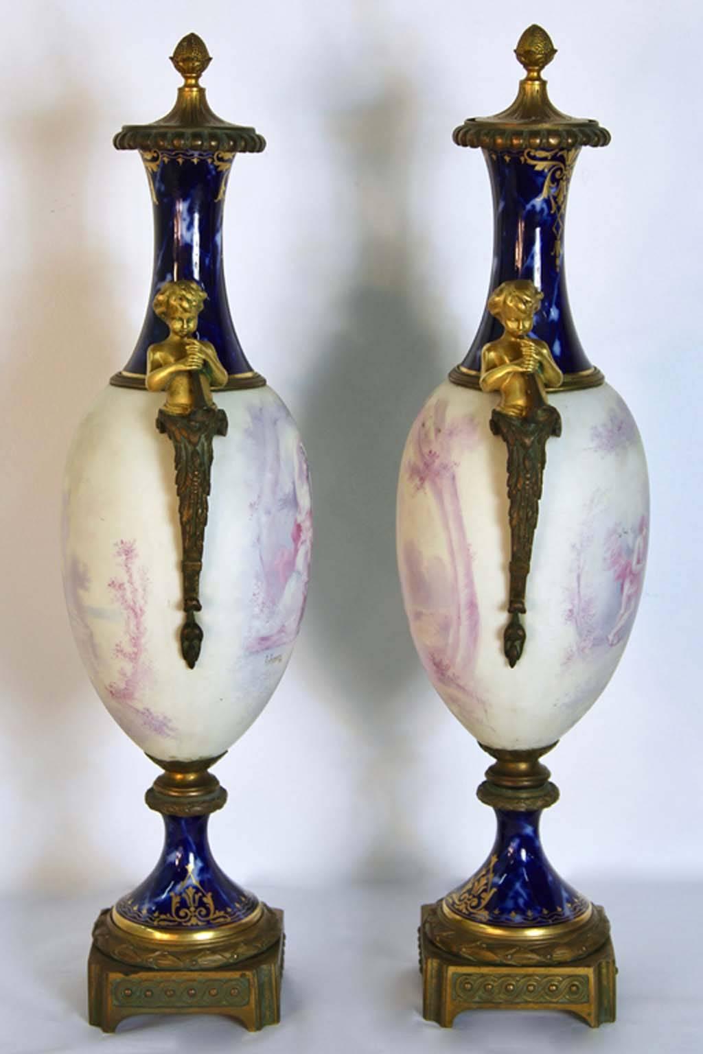 A rare pair of sevres urns with gilt bronze figural sculpture mounts of a young boy playing trumpet on the sides. Having a unique cobalt marbleized porcelain neck and base with pastel romantic scenes painted on both sides. Body rotates to show both