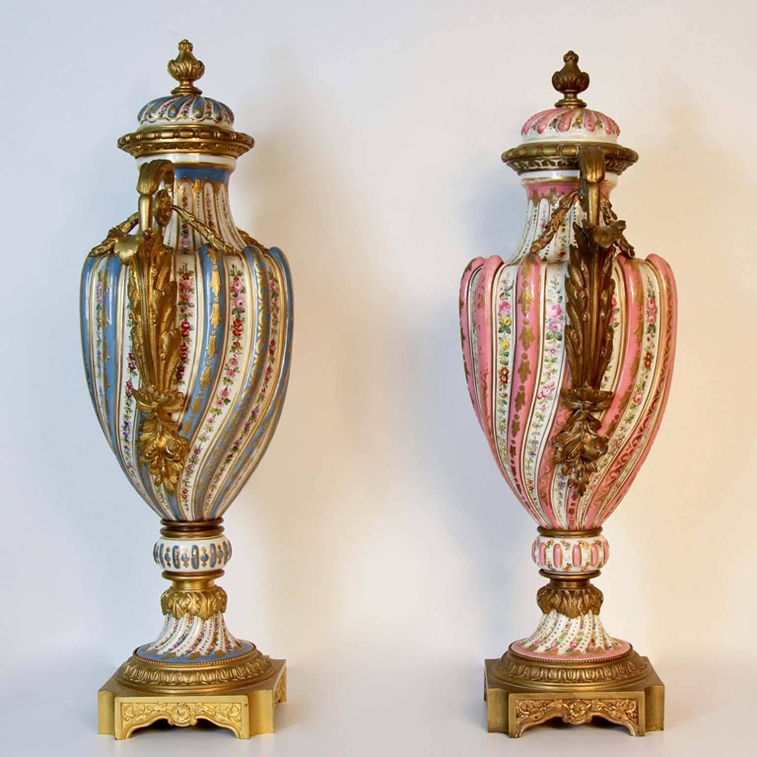 Two fine large 19th century French Sevres urns in celeste blue and pink porcelain. Having rich raised gold enamel decoration with roses and leaves adorning each urn. Museum quality cast bronze mounts all original as side handles, base and top with