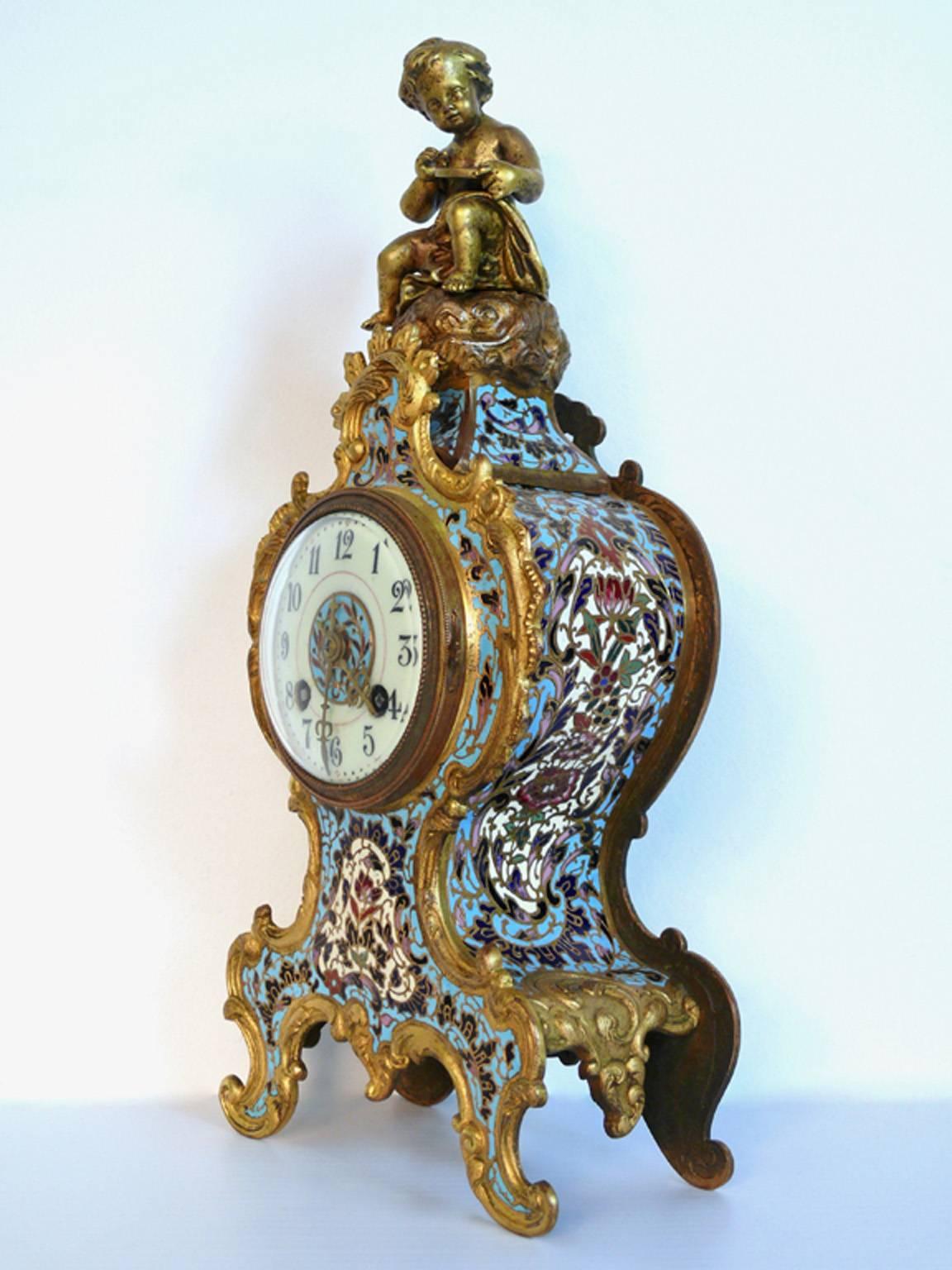 A fine gild gold ormolu and doré bronze French clock with cherub on top. Having the highest quality enamel work much like Russian Faberge in baby blue colors. Rare from with happy floral design. All original clock movement in tact.