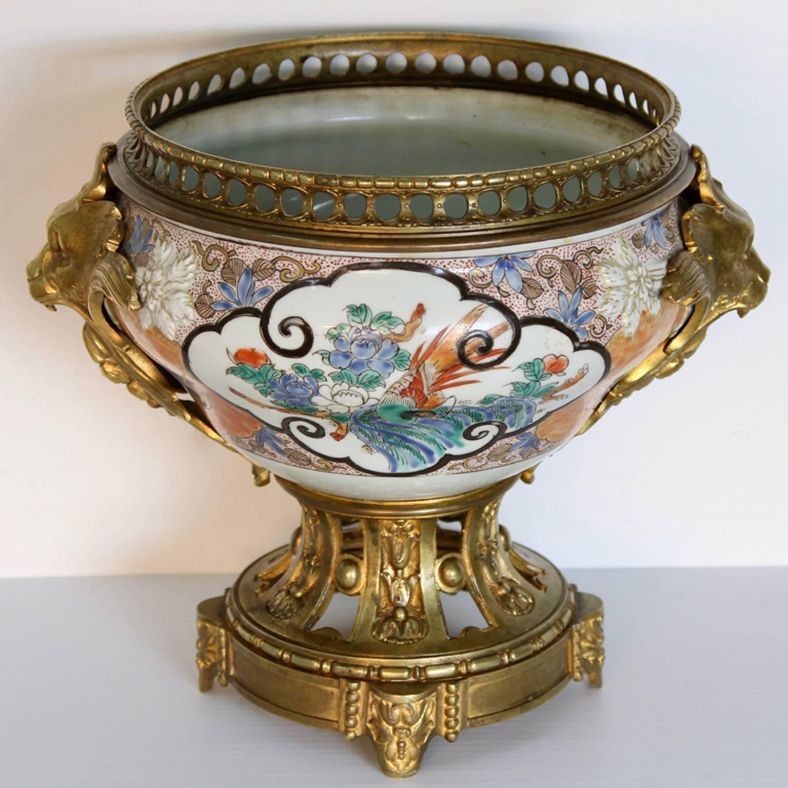 An Oriental porcelain centerpiece, signed, with mercury guided French doré bronze ormolu mounts, circa 1700s-early 1800s. Having golden bronze ferocious lion mounts on the side with a reticulated bronze base supporting the museum quality oriental