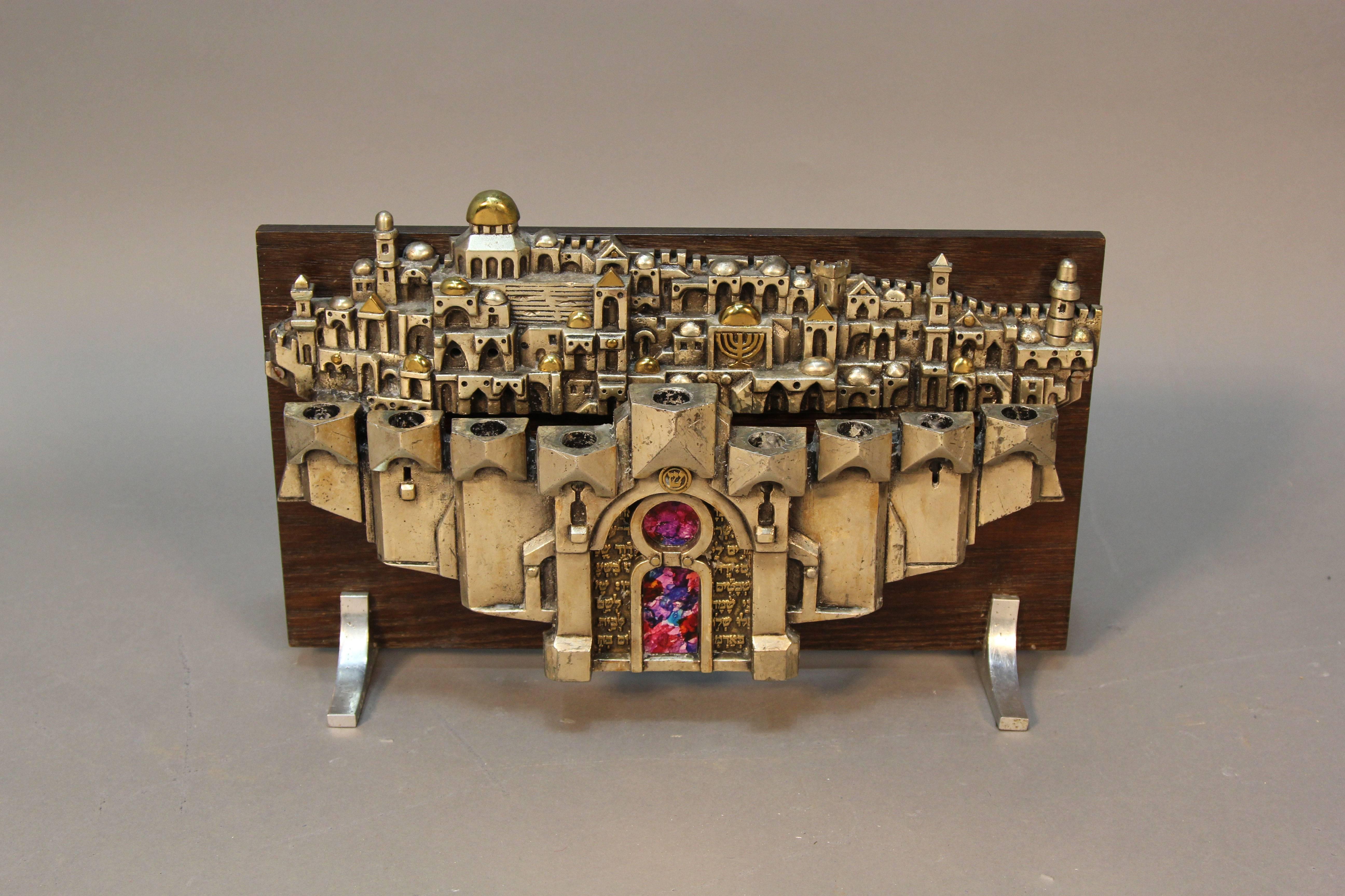 Artist signed Frank Meisler nine-branch Hannukah menorah sculpture. The sculpture features the hills and gates of Jerusalem and is sculpted of mixed metals and plated with gold and silver. Overall 19” wide and 12-3/4” high. Highly collectible art by