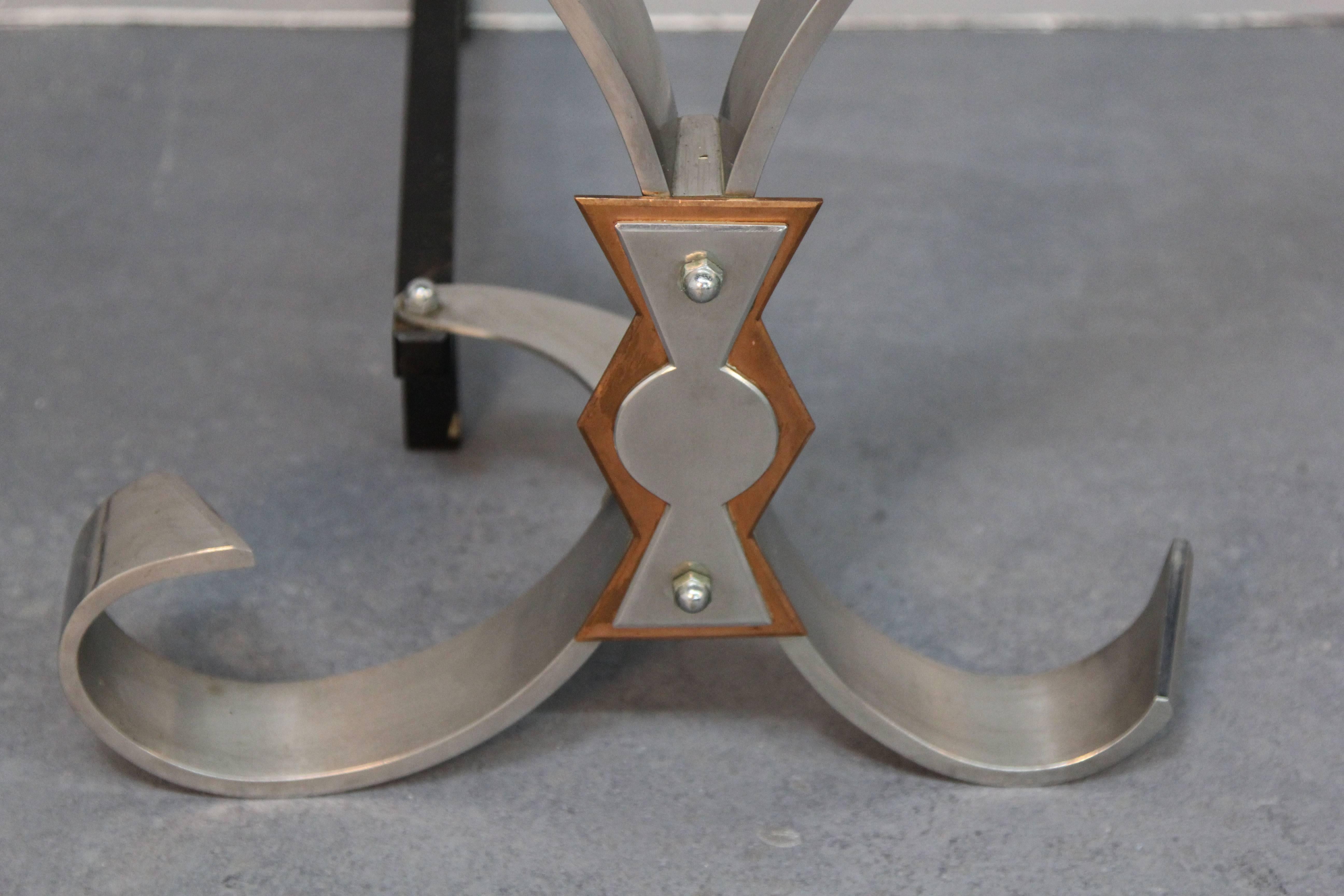 Pair of polished steel andirons with applied copper and steel elements and iron billet bars.

