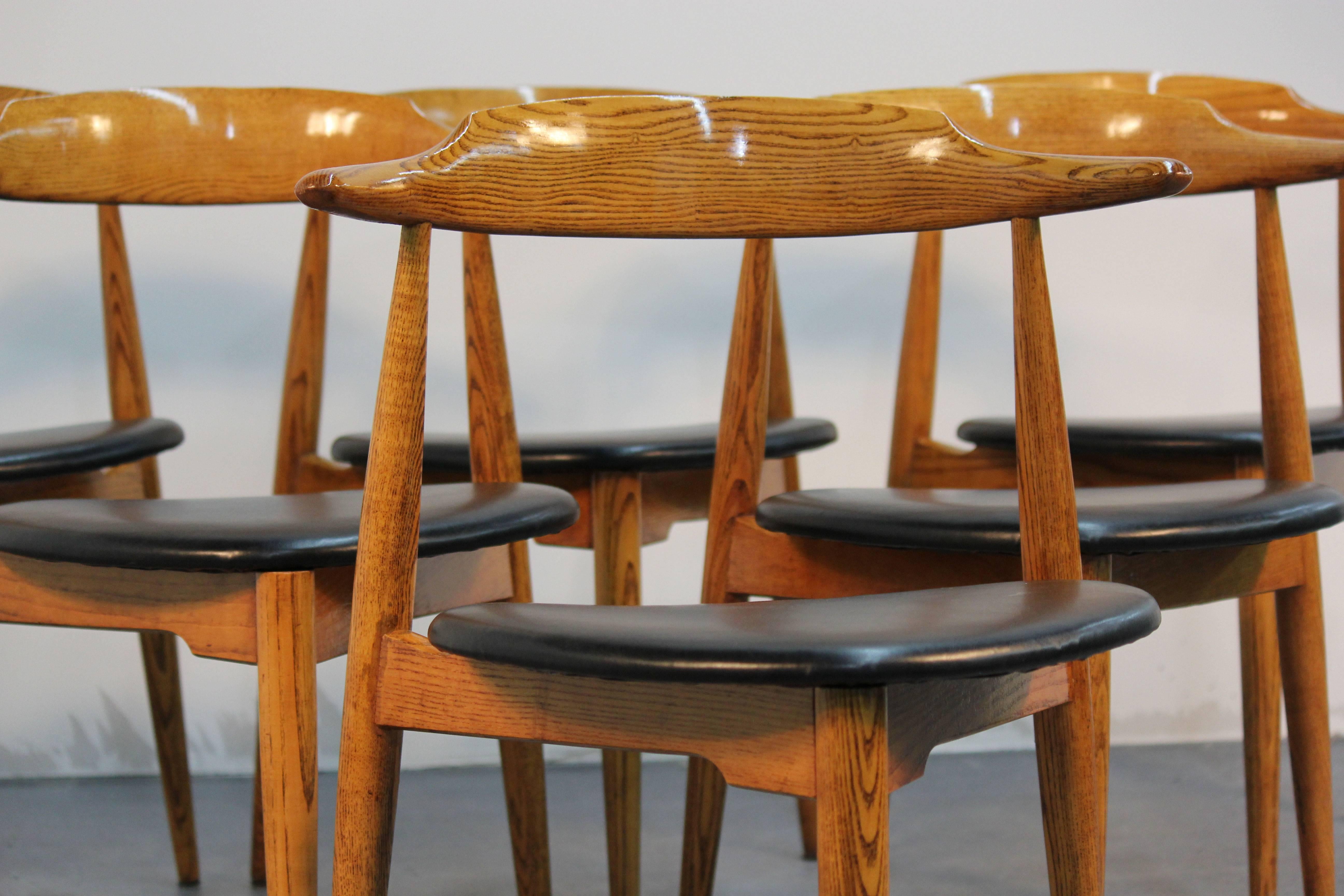 Newly refinished and newly upholstered in black vinyl "Heart" chairs by Hans Wegner. Bullhorn backs, three legged in oakwood.