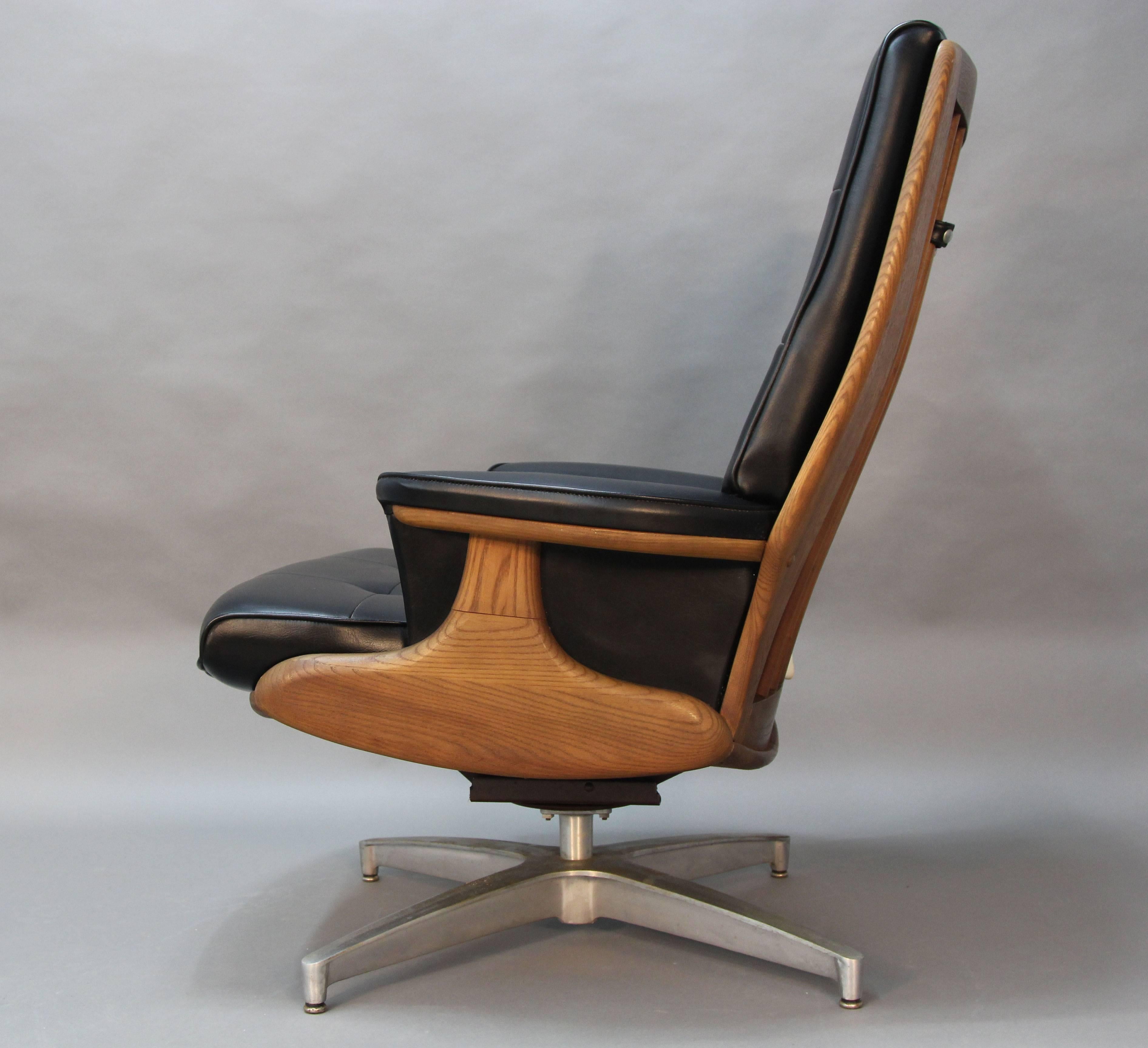 Excellent condition, Heywood-Wakefield Mid-Century lounge chair and ottoman. Wood frame on metal swivel base. Vinyl upholstery with box stitch and button tufting.