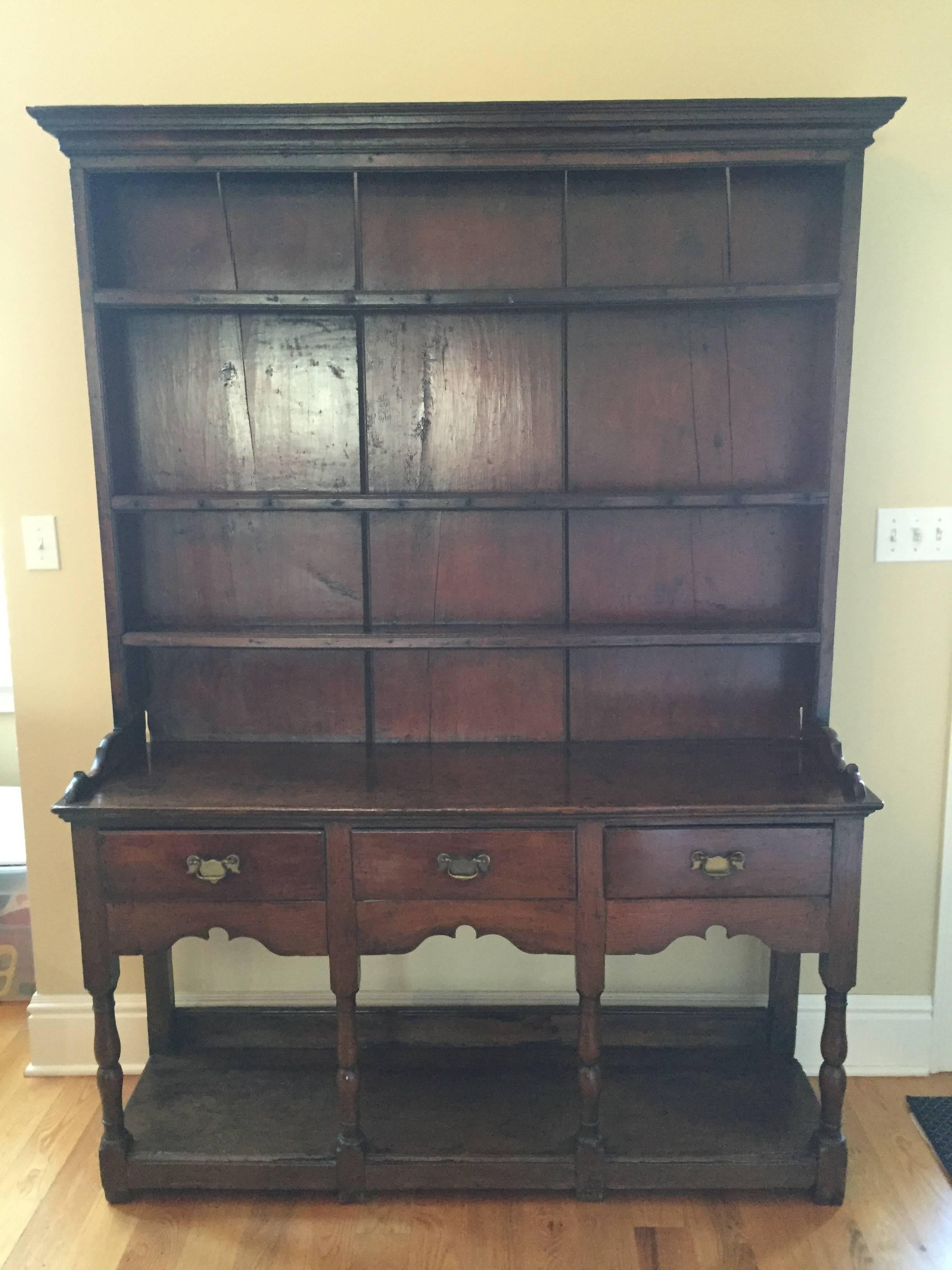 Rare Small Welsh Oak Dresser with rack and pot board to base.  Upper part has carved and shaped cornice and three shelves.  Three drawer below shelves.  Front legs are turned with block feet.  C. 1770