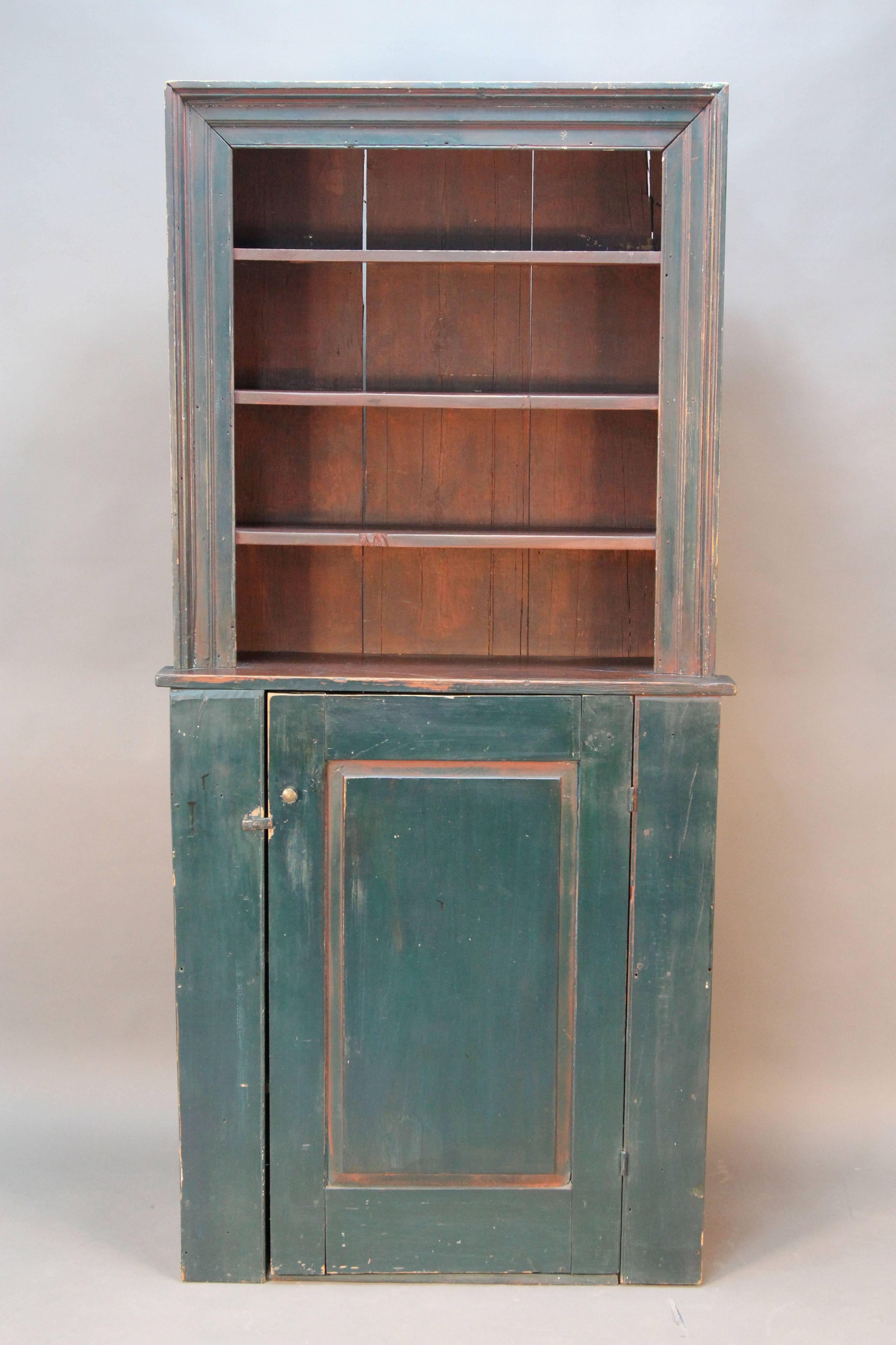 Primitive stepback cupboard with elegant trim. Original red milk paint, blue green painted addend in late 1800s. Solid wood construction with square nails and wood pegs. Made of pine.