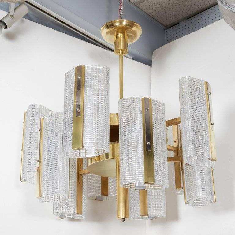 Very large Art Moderne highly architectural ten-arm chandelier comprising bi level rectangular boxes of interlacing lines in a grid pattern mounted in a polished brass armature.
The crystal glass boxes glisten and shimmer in the light creating an