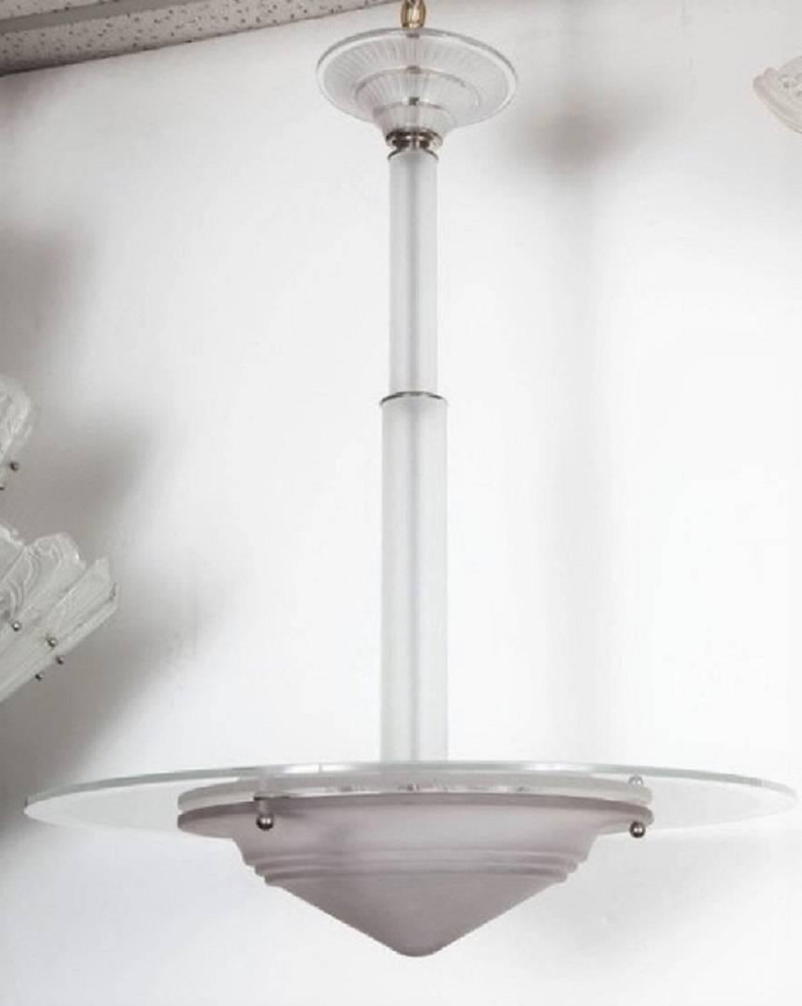 Modernist chandelier comprising a sleek and simple frosted art glass coupe with disc surmount suspended by a frosted tubular stepped stem topped by a linear glass canopy.
This chandelier can be shortened for a surcharge.
Newly wired for US specs.