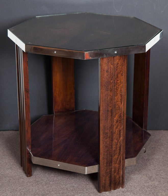 A handsome lacquered French Modern octagonal table in bookmatched walnut with four fluted slab legs, a bottom stretcher shelf, nickeled bronze mounts, featuring a protective glass top.
Can be used as a pedestal, sofa table, night table,