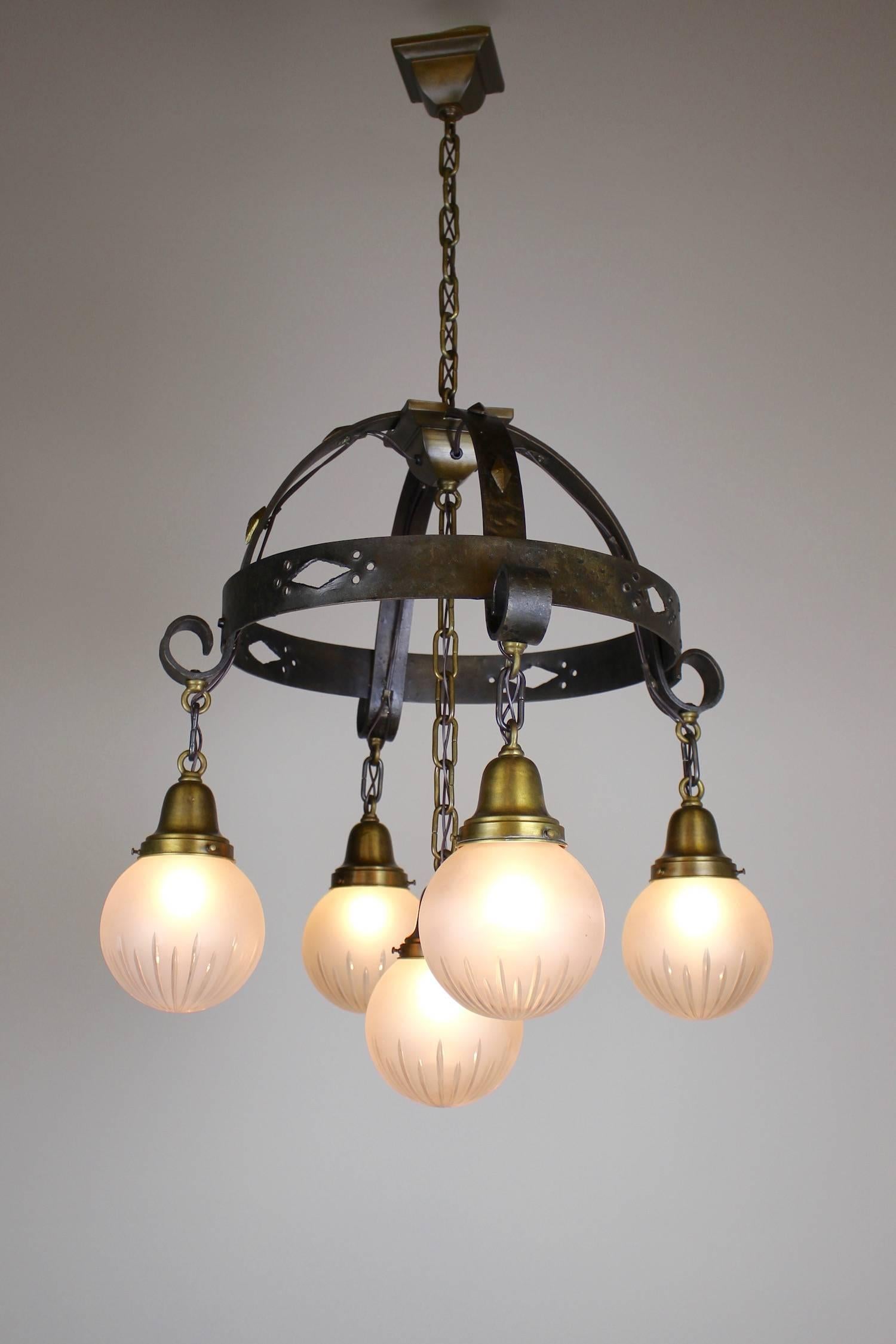 This is a wonderful example of handcrafted arts and crafts lighting by Beardslee of Chicago, circa 1920. This five-light ring fixture is hammered iron with punched cut-out and diamond stud detail. Fitted with wheel cut ball shades this is a