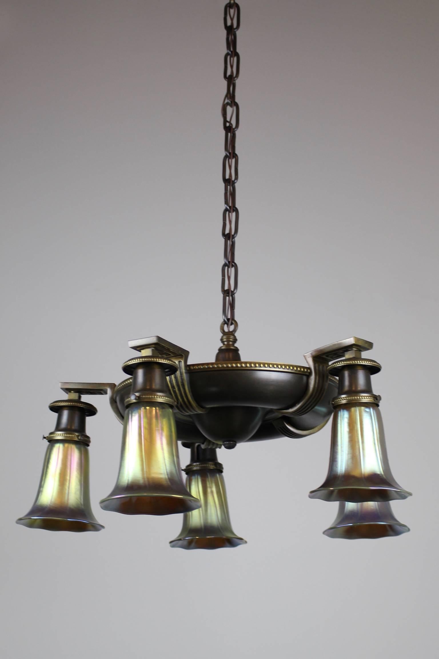 This is a lovely five-arm Classical Revival pan fixture by Shapiro & Aronson, circa 1925. This fixture has refined Neo-Classical lines, with two-tone brass detail. Fitted with five aurene art glass shades, made in the manner of Steuben. Cleaned,