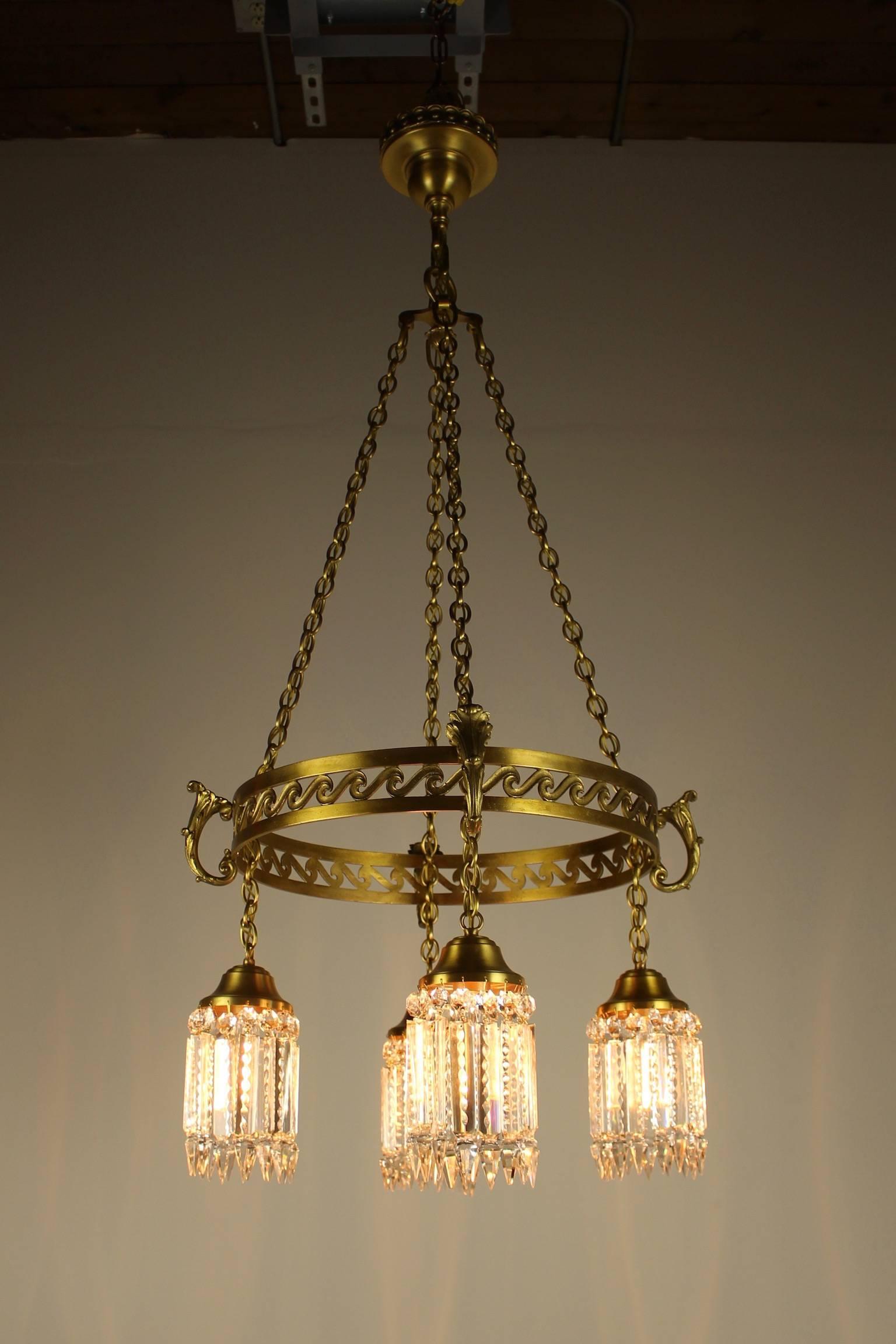 A beautiful and early example of the neoclassical style influencing early American lighting, circa 1905. This brass ring fixture is elegantly decorated with an 'S' curl motif with acanthus leaf appointments denoting every holder. This four-light