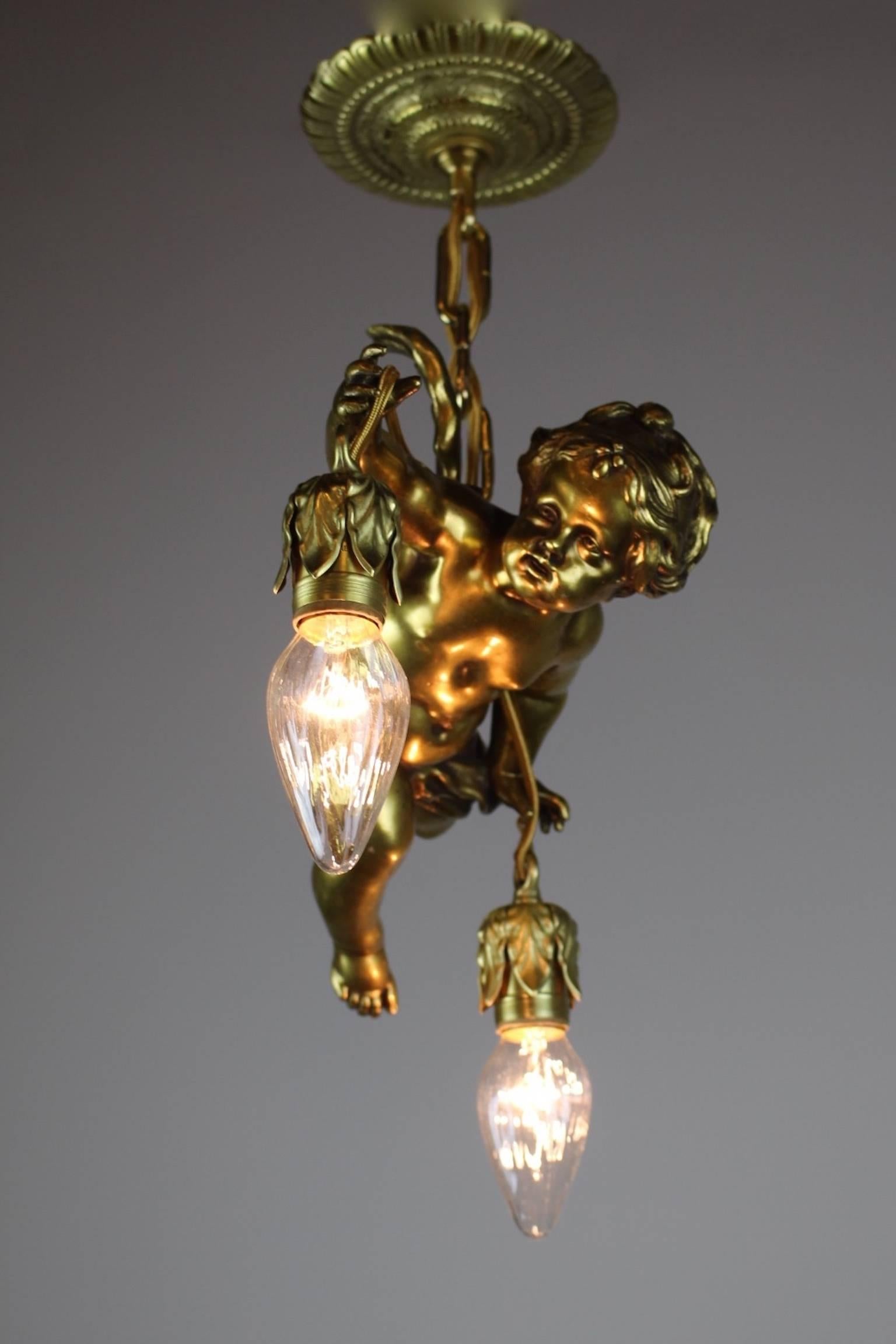 A quality fixture in the Renaissance Revival style, circa 1915. The body of a cherub flying through the air makes up this antique light, cherub holds the lights delicately in his hands.

Measurements: 22"in L x 16" in. D
 