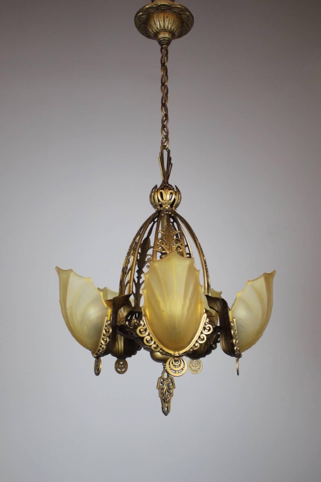 A beautiful and original Art Deco slip-shade fixture, circa 1920. These gorgeous shades are in a frosted honey amber tone. Gorgeously decorated cut-out brass body in a warm bronze tone. Wonderful for a dining room, entryway, or living room.