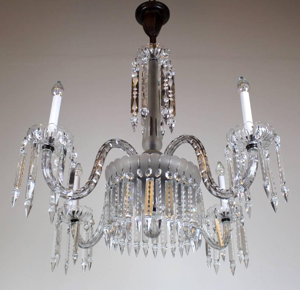 A simple, yet stunning Victorian crystal chandelier converted from gas to electric.

Four elegantly curved arms ending in floral cups. Central shaft has crisp, clean designs cut into it.

Overall has a Georgian revival style to it. The piece is