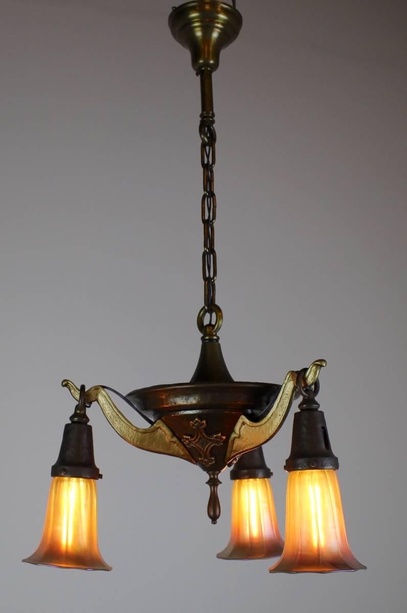 Attributed to McKenney of Boston, this hammered iron fixture is finished in a two tone scheme, with lovely cross details.

Fitted with gold Aurene art glass shades, 

circa 1912.

Measures: 34