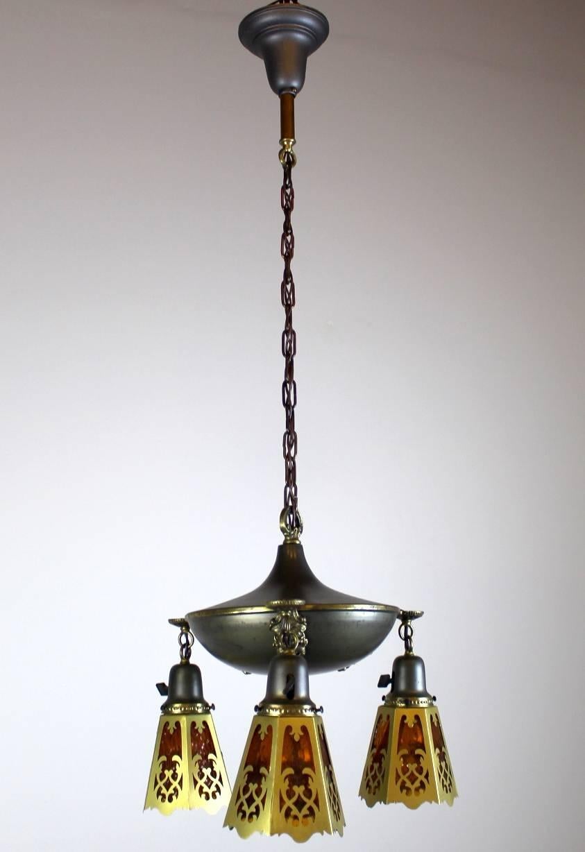 Interesting two-tone Art Nouveau inspired fixture.
Original finish, gun metal and polished brass highlights.
Three arms, finished with amber ripple glass cut-out shades.
circa 1915
Measures: 41