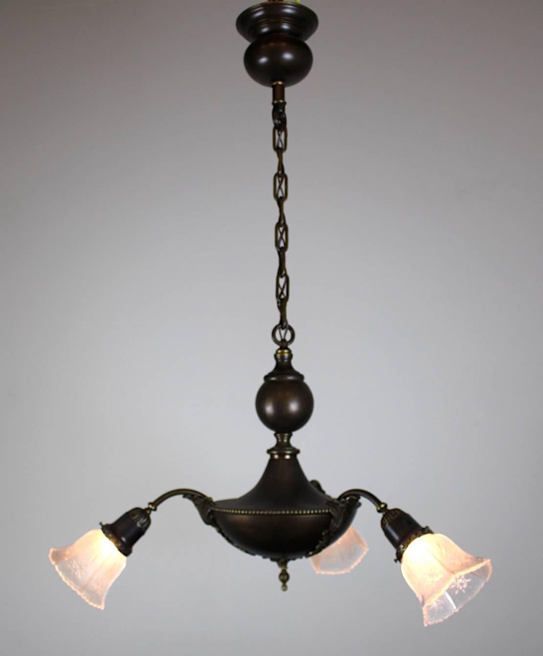 Three-light pan fixture, with interesting decorative elements.

The 'ball' motif twinning canopy and body really tie the fixture together visually.

3 shallow angled arms ending in clear embossed shades.

Finished in a dark chocolate bronze