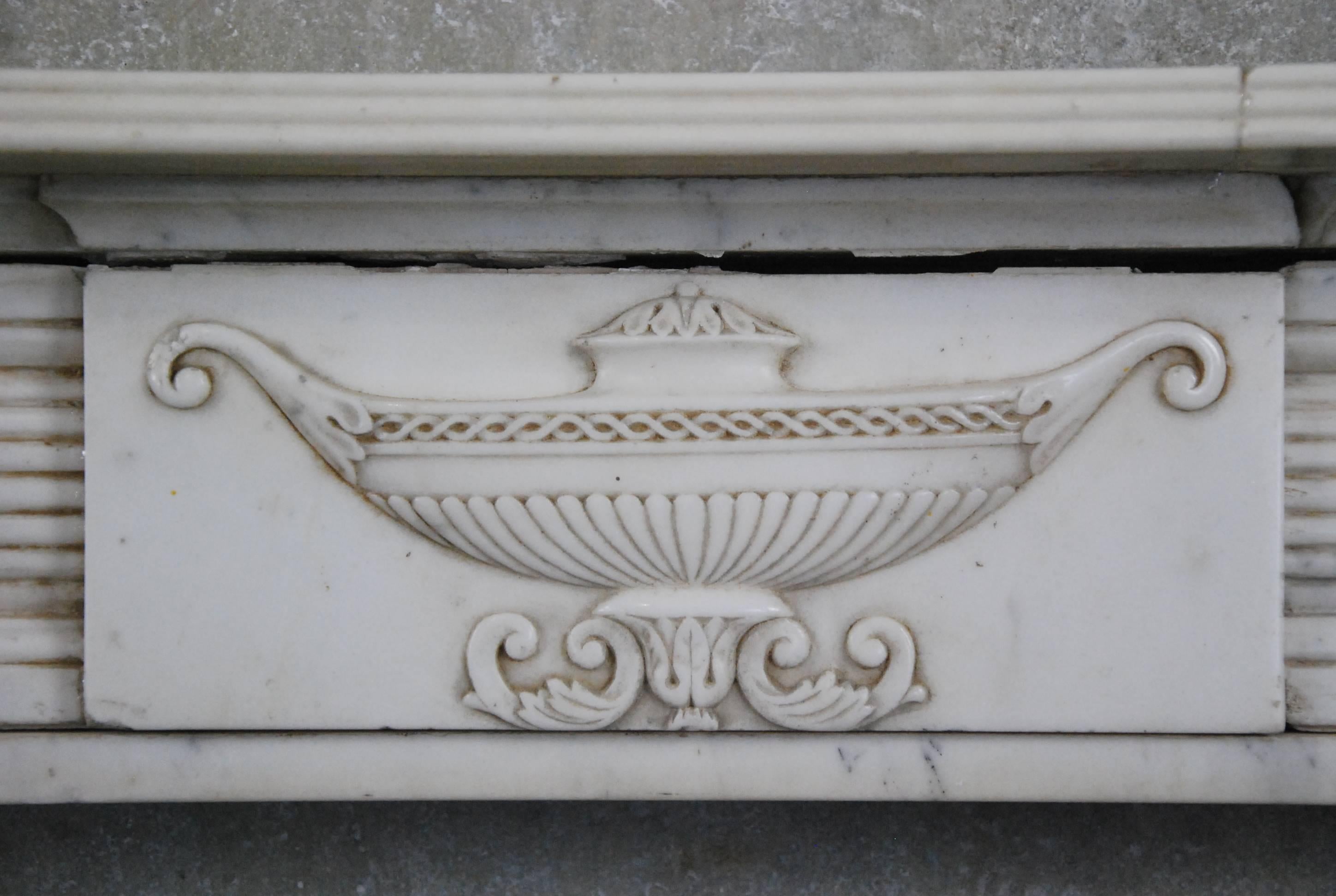 19th century English fireplace surround in Italian Carrara marble. Fluted columns and relief carved centre urn. Recently acquisition from a collection where items were purchased in 1970 in Europe. Very easy install.