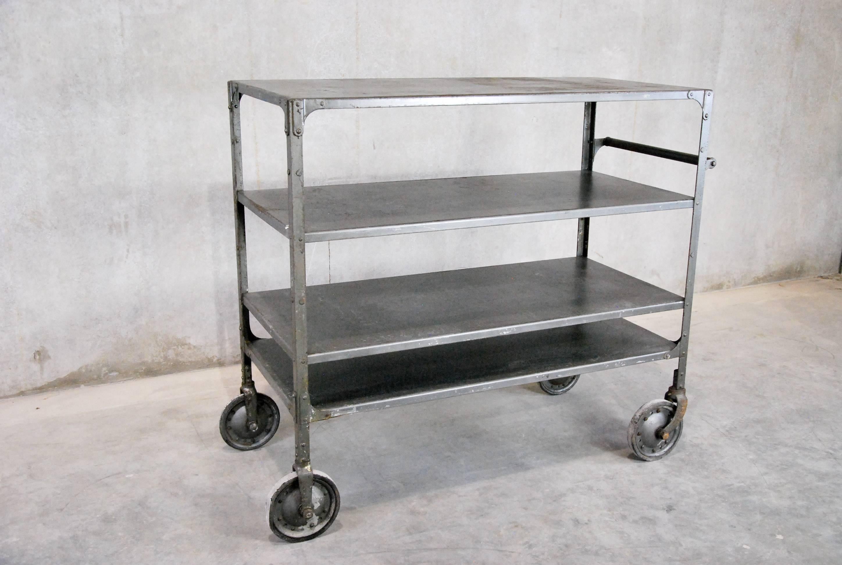 American made reinforced steel with multi-tiered shelving on factory wheels.
Piece is in original old finish and with push handle.

Found in a factory in Pacific North West.
 