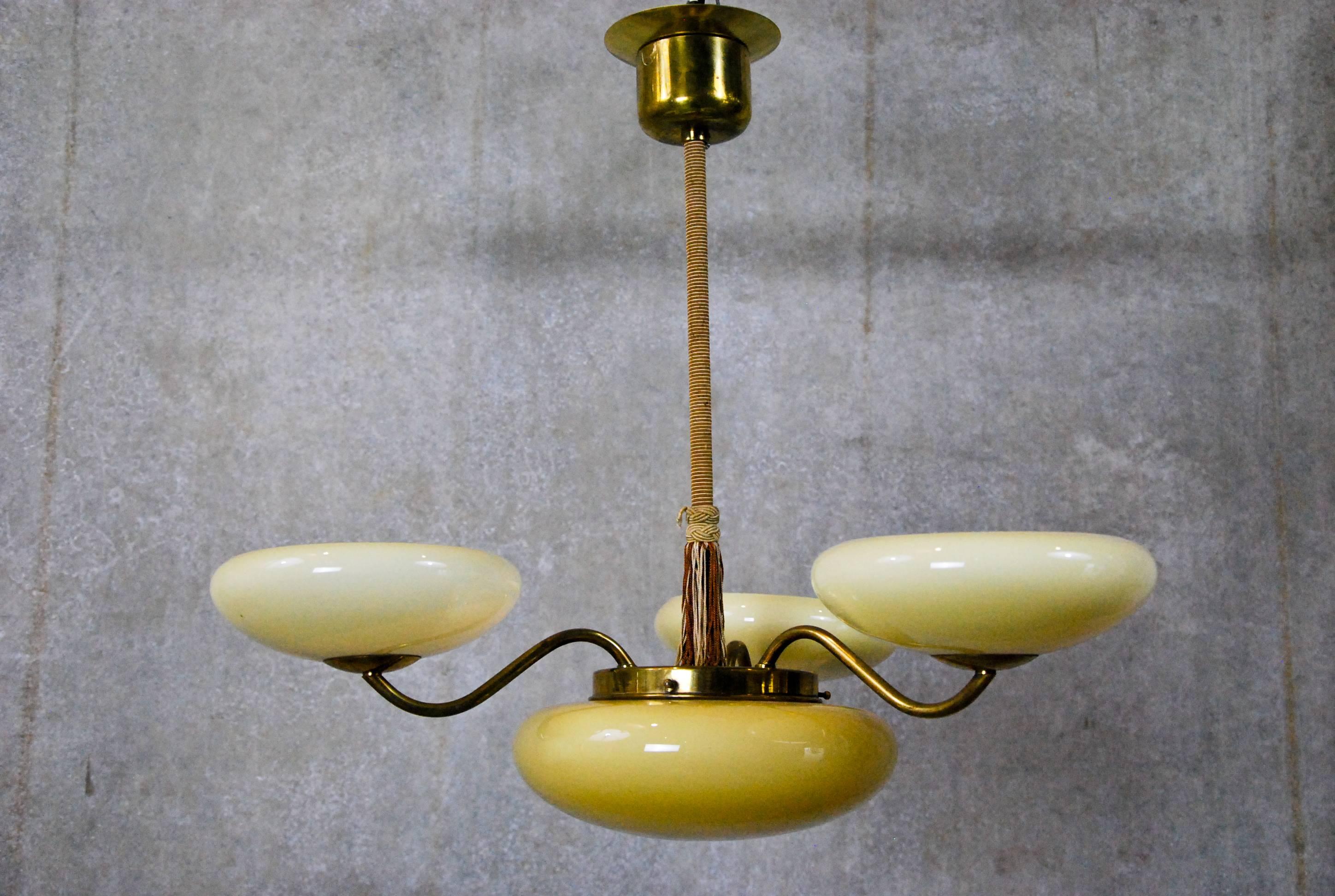 A three-light, brass and amber glass chandelier with adjustable arms. Hollywood Regency style; probably from the 1940s.
Amber cased glass is typical of Italian (Murano) glass of that period.
Great transitional chandelier.
Note- cloth threaded