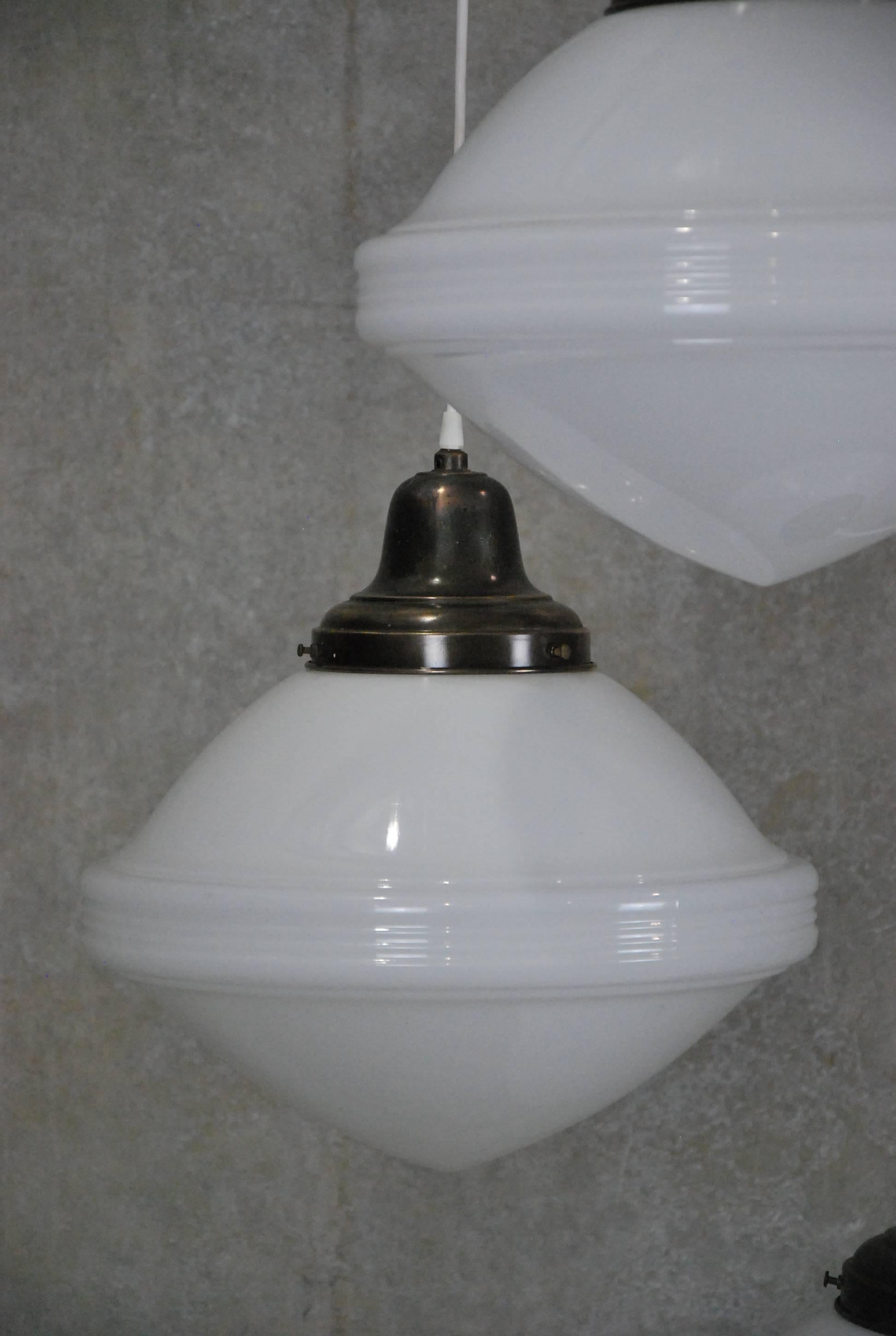 Oversized, 1920s milk glass pendants with original copper fitter. Found in Eastern USA. Re-wired and CSA approved; ceiling mounting cap included. Quantity of three in stock. Price per item.
