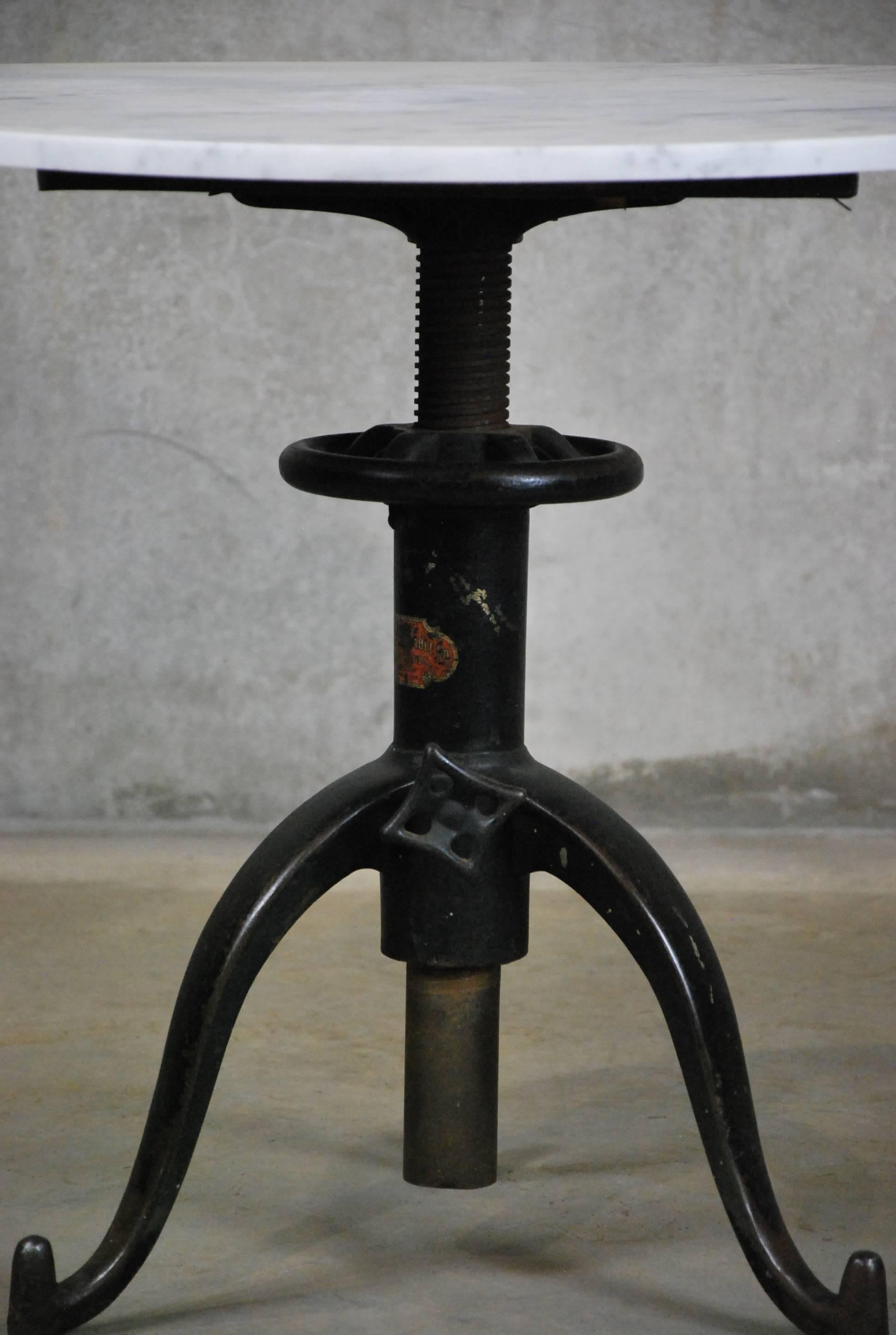 
Beautiful cast iron base with 30 inch Carrara marble top.

The base is made by Satellite Adjustable Table Co. from Grand Rapids Michigan. It is solid metal with many adjustable pieces. It sits on three wheels that all move freely. The company