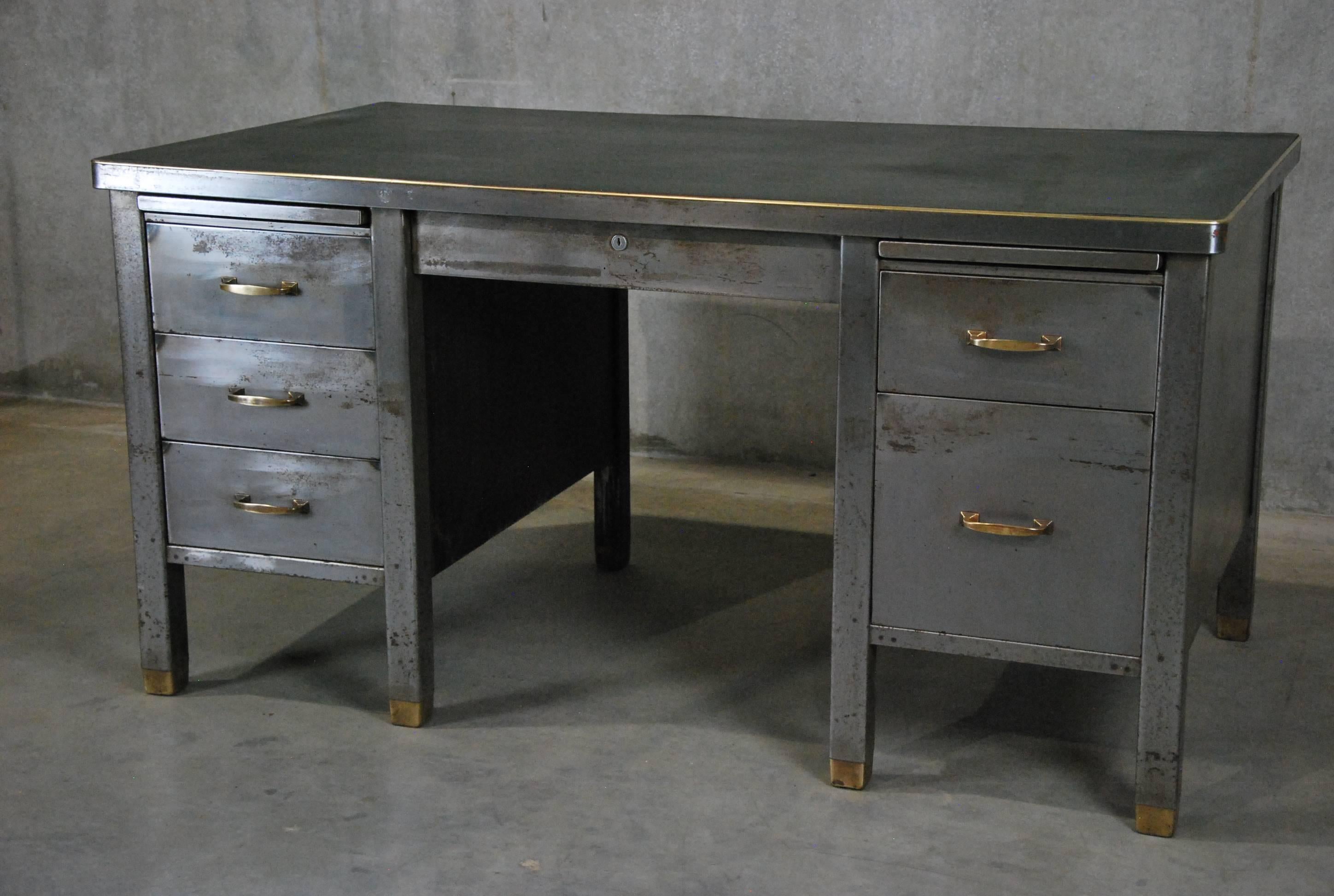 Very nice cleaned down and hand polished metal Mid-Century desk with wonderful brass hi lights functioning drawers and original faux leather green top.

Very solid.