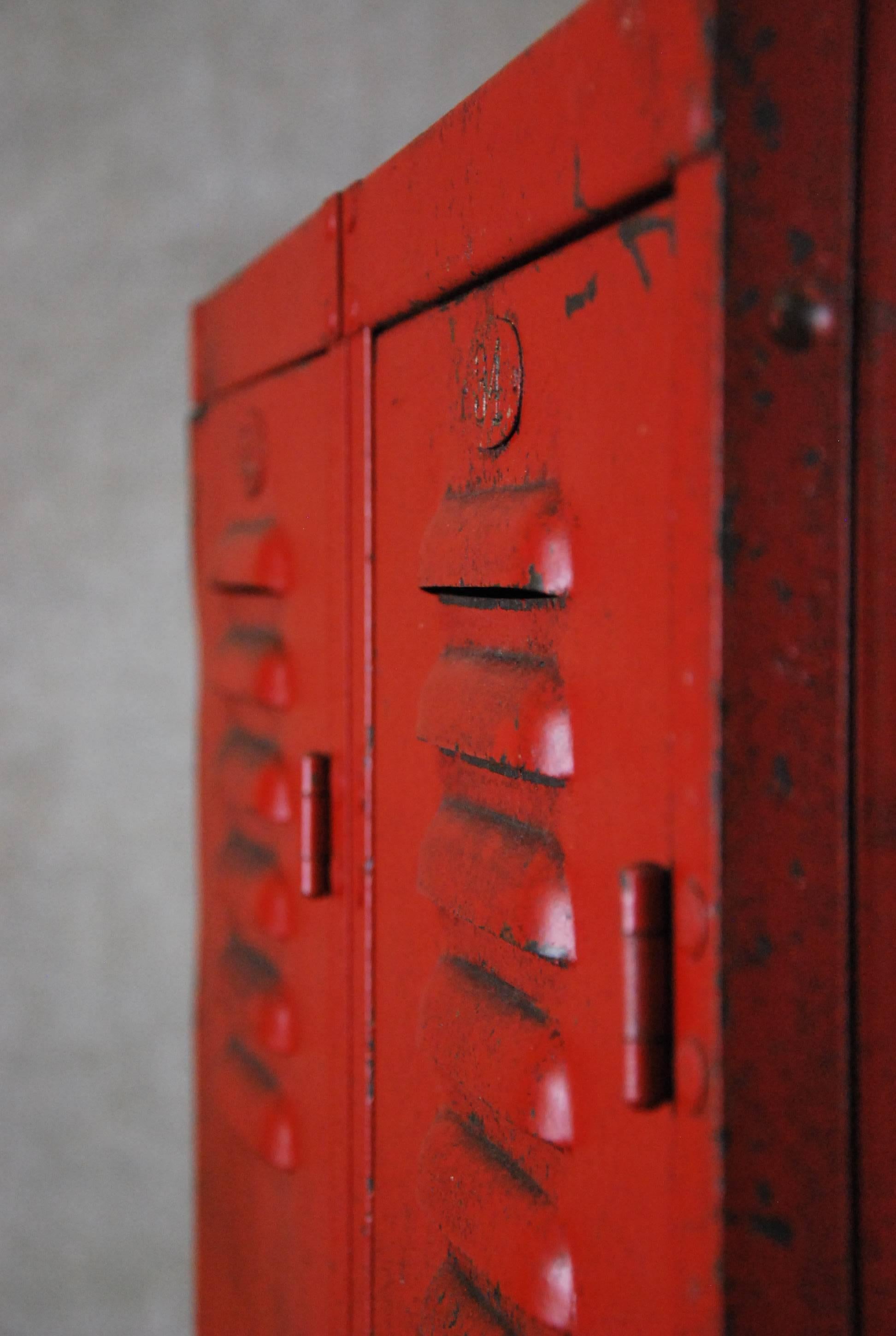 Early 20th century vintage Industrial double unit freestanding locker comprised of a heavy gauge steel with riveted joints with original red paint finish. The hinged locker doors feature louvered vents on both the top and bottom.

Fabricated by