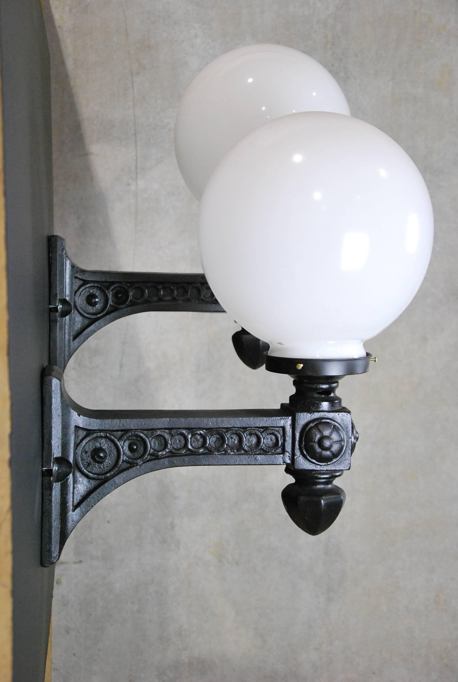 Pair of rewired and refurbished cast iron sconces, salvaged from a building in Chicago 20 years ago. Lights are CSA approved and ready to install. The 10-inch round glass globes are most likely not original but the fitter is a typical 6-inch, so