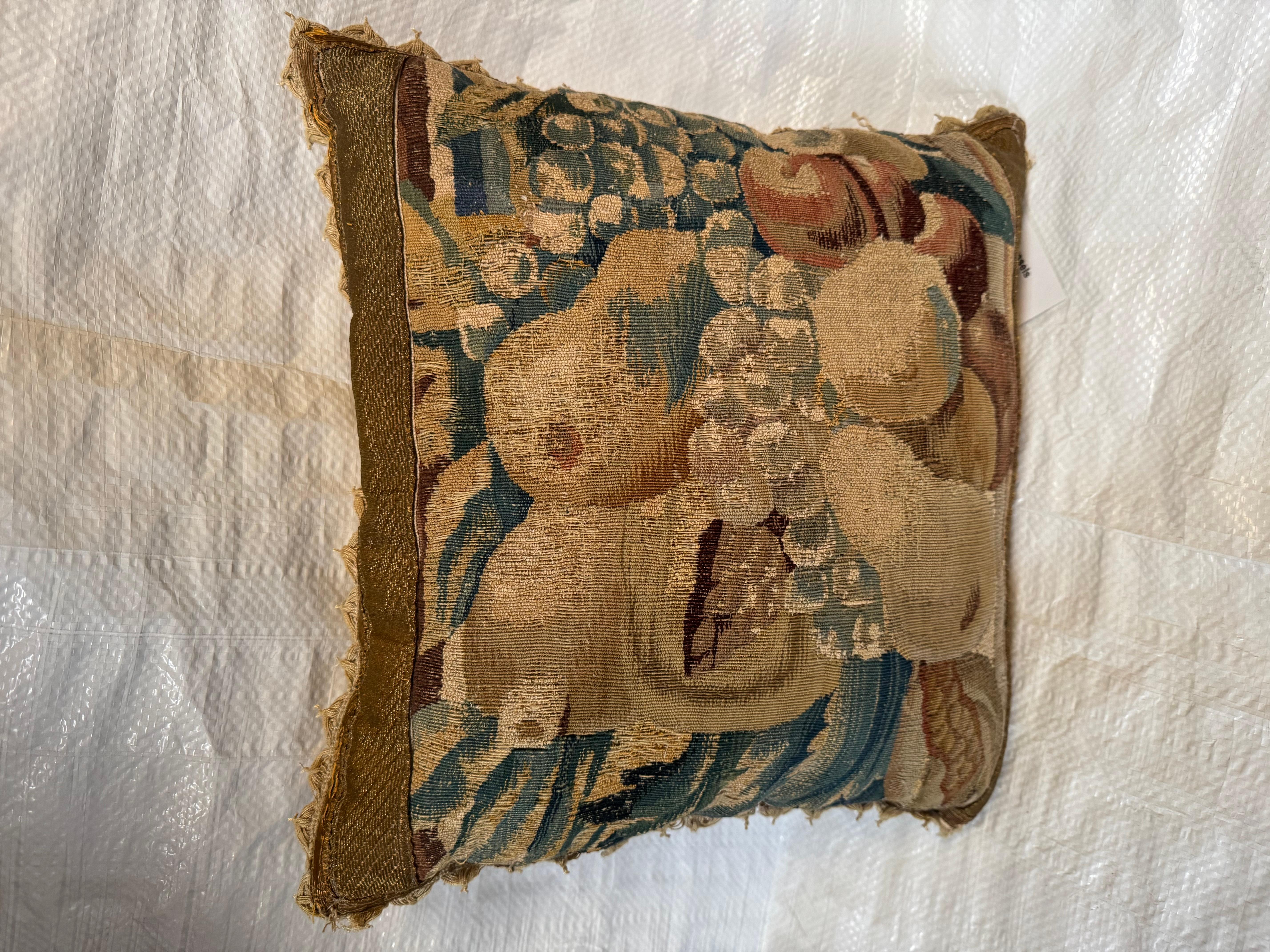 Un oreiller décoratif unique fabriqué à partir d'un authentique fragment de tapisserie bruxelloise du XVIIe siècle. Cette pièce présente un motif de nature morte richement tissé, faisant probablement partie d'une plus grande scène flamande de