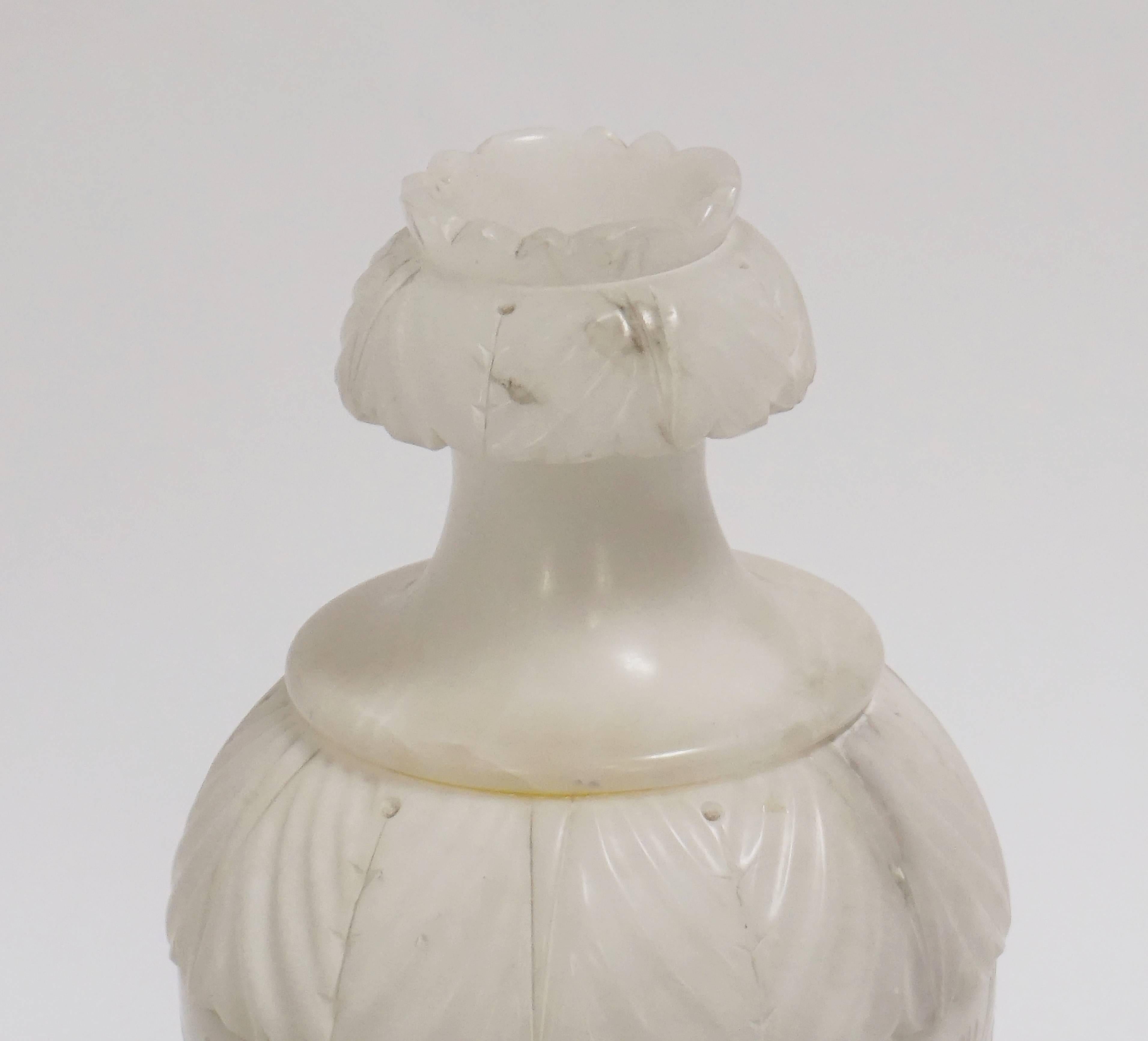 This Alabaster urn table lamp is lidded with interior sockets. The lid has an opening at the top. Delicate details are carved throughout. Single interior candelabra socket with a switch on the cord.