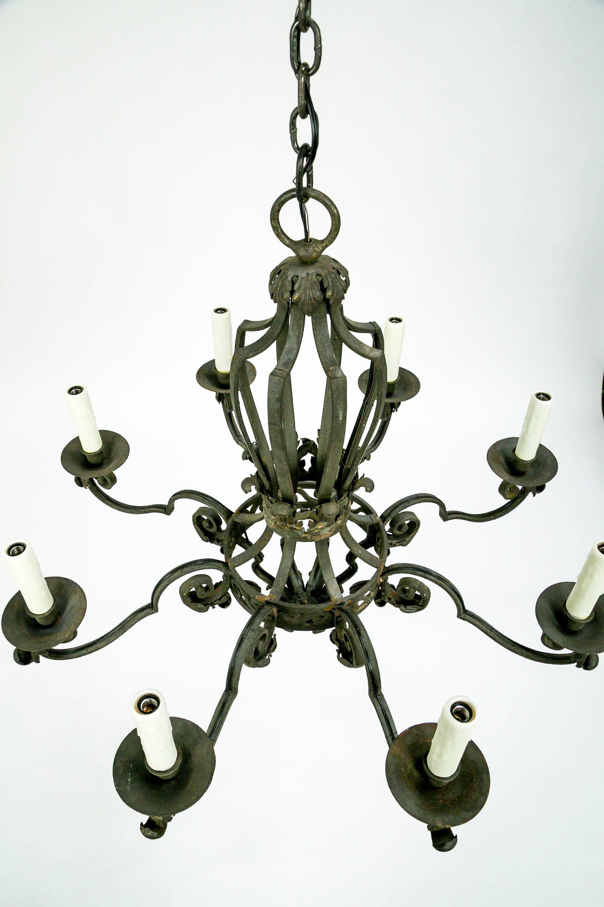 This dignified, eight-light chandelier is made from hand-forged wrought iron in 1860s, France. It has an eye-catching shape with leaf accents and canopy shape. Recently rewired; resin candle covers. 29.5