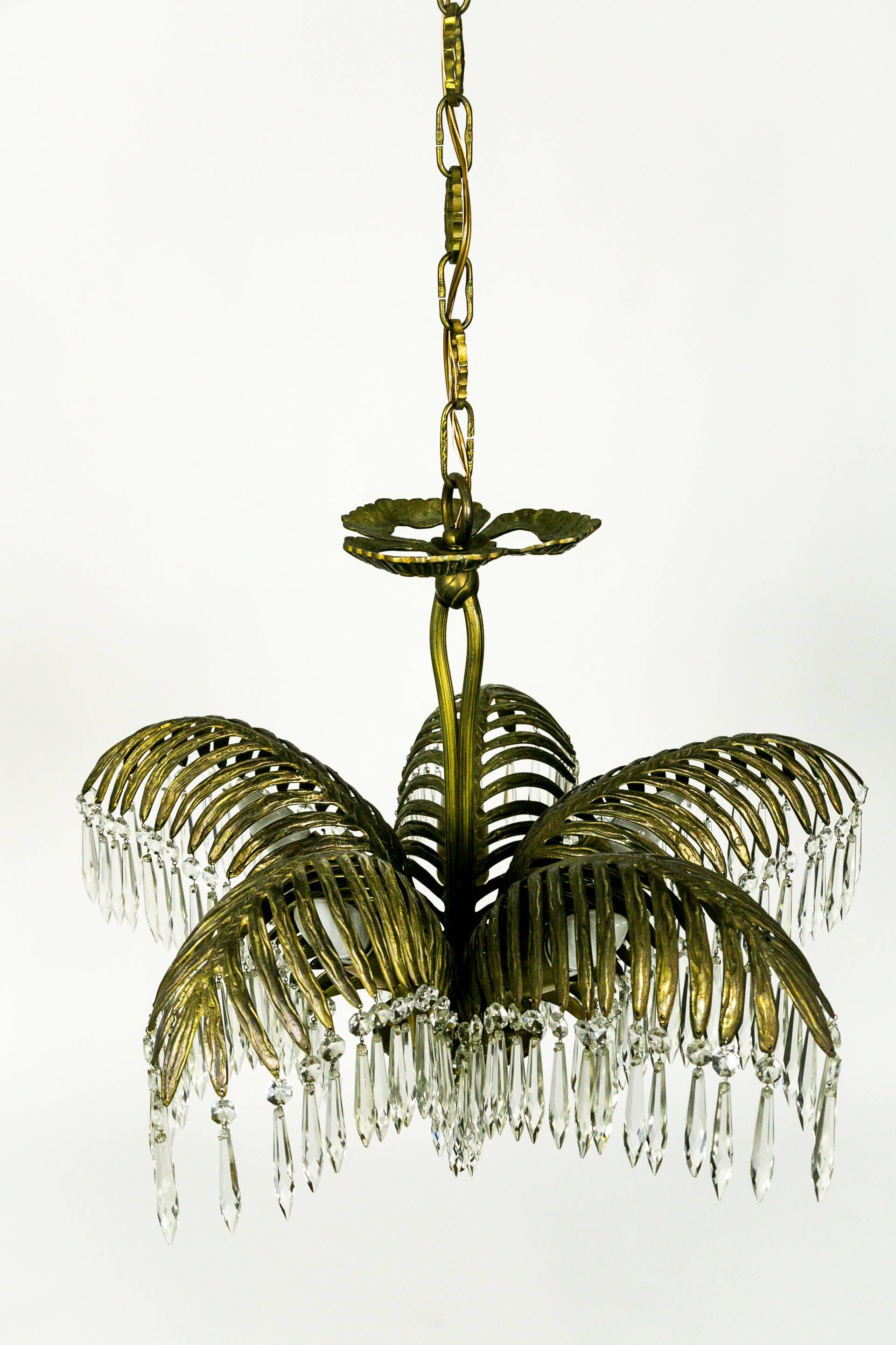 This eye-catching, Regency Style, brass, five-palm frond chandelier drips with octagon and icicle crystals. It has a decorative rope stem continuing as a tassel finial, and a beautiful three-petal upper bobeche. French. Five-sockets. Newly restored