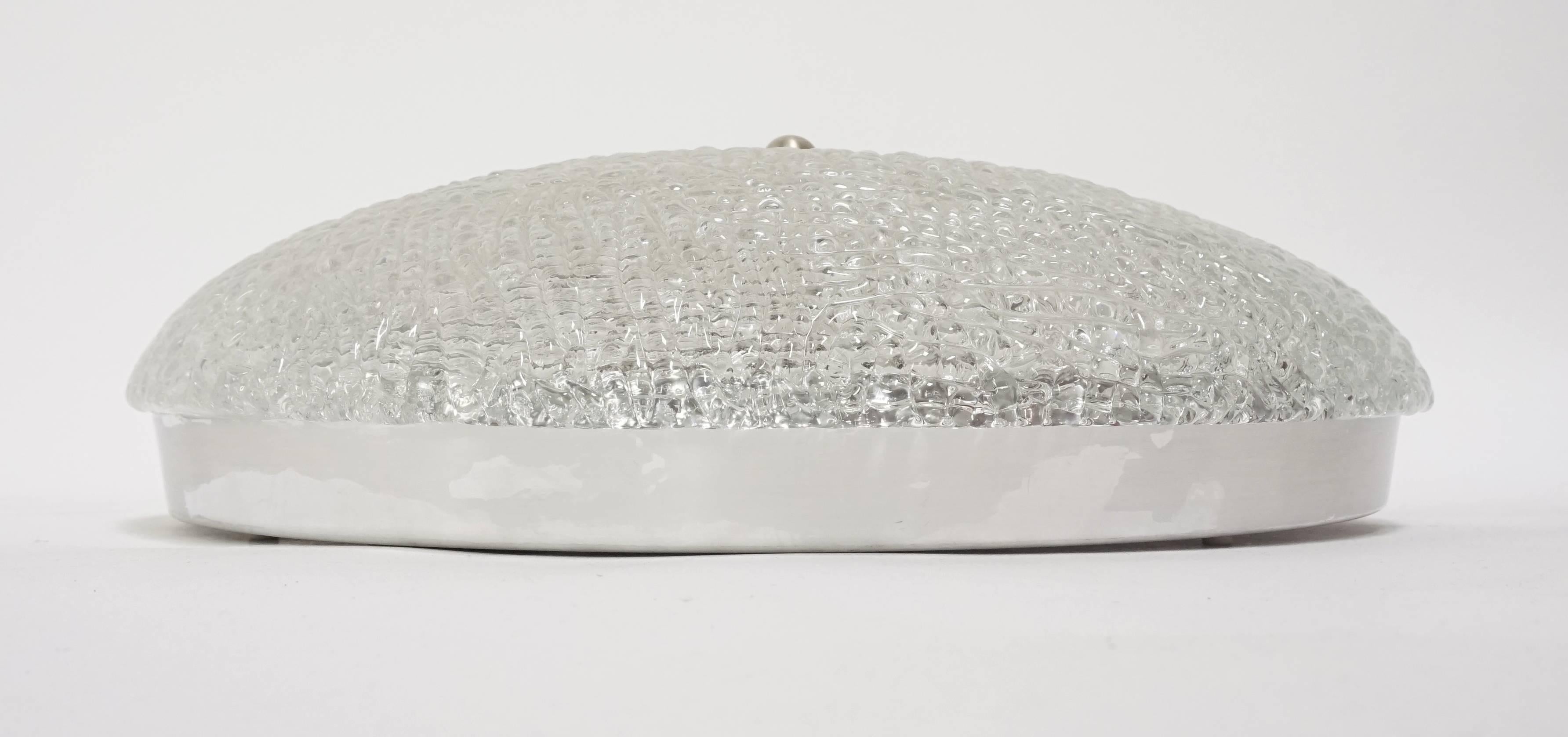A wonderful round ice glass flush mount, by Kalmar, Austria, 1960s.
Thick textured ice glass fixture on a metal base. Newly rewired. UL listing available for an additional fee.