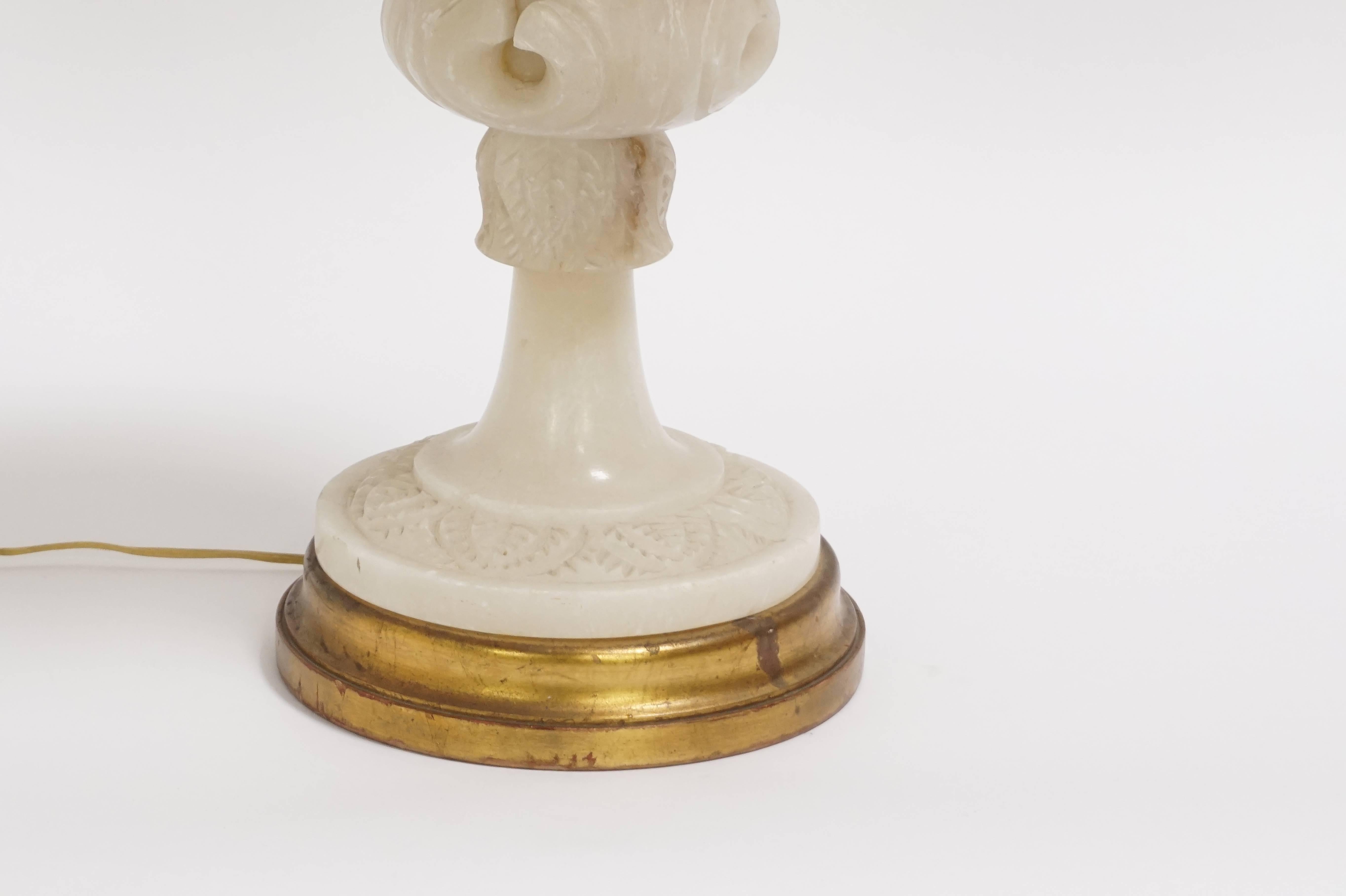 This gorgeous, Italian carved alabaster table lamp illuminates from within to magnify the character of the stone.  Looks lovely both on and off.  It has a palmette design on a gilded base.  Two internal sockets, one on neck.  Brass hardware, wiring