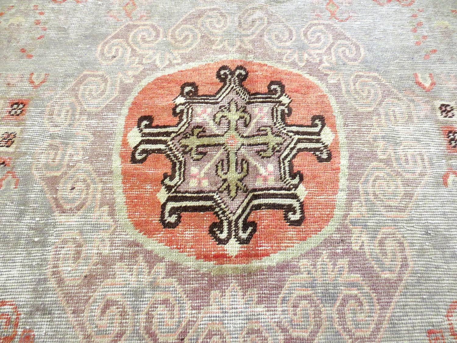 Dieser antike Khotan-Teppich stammt aus Ostturkestan, etwa aus den 1880er Jahren. Dies ist ein schönes Beispiel für die frühen Khotan-Teppiche aus dieser Region mit weichen grauen Feldern, Rot-, Braun-, Elfenbein- und Korallenfarben. Ein kleines