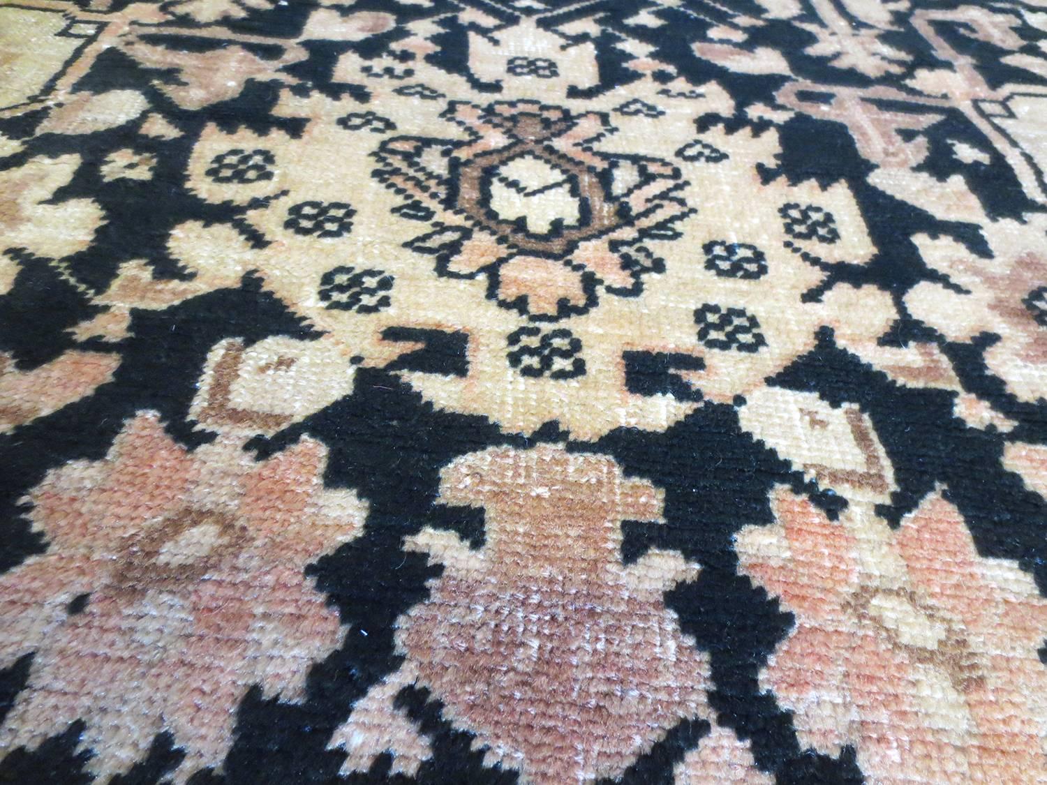 This is an antique Karabagh runner from the Caucasus area circa 1880s. It has a regal display of palmette, floral and angular patterns on dark black field with light peach, ivory, taupe and browns. The darker field is nicely offset by a softer