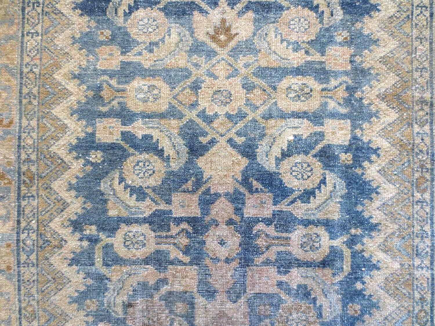 This is an exquisite antique Persian Malayer, circa 1900s. Geometric floral designs pattern down a light blue field. Its forms are defined further by shades of ivory, taupe, olive, and hints of yellow that contrast well with the background. A series