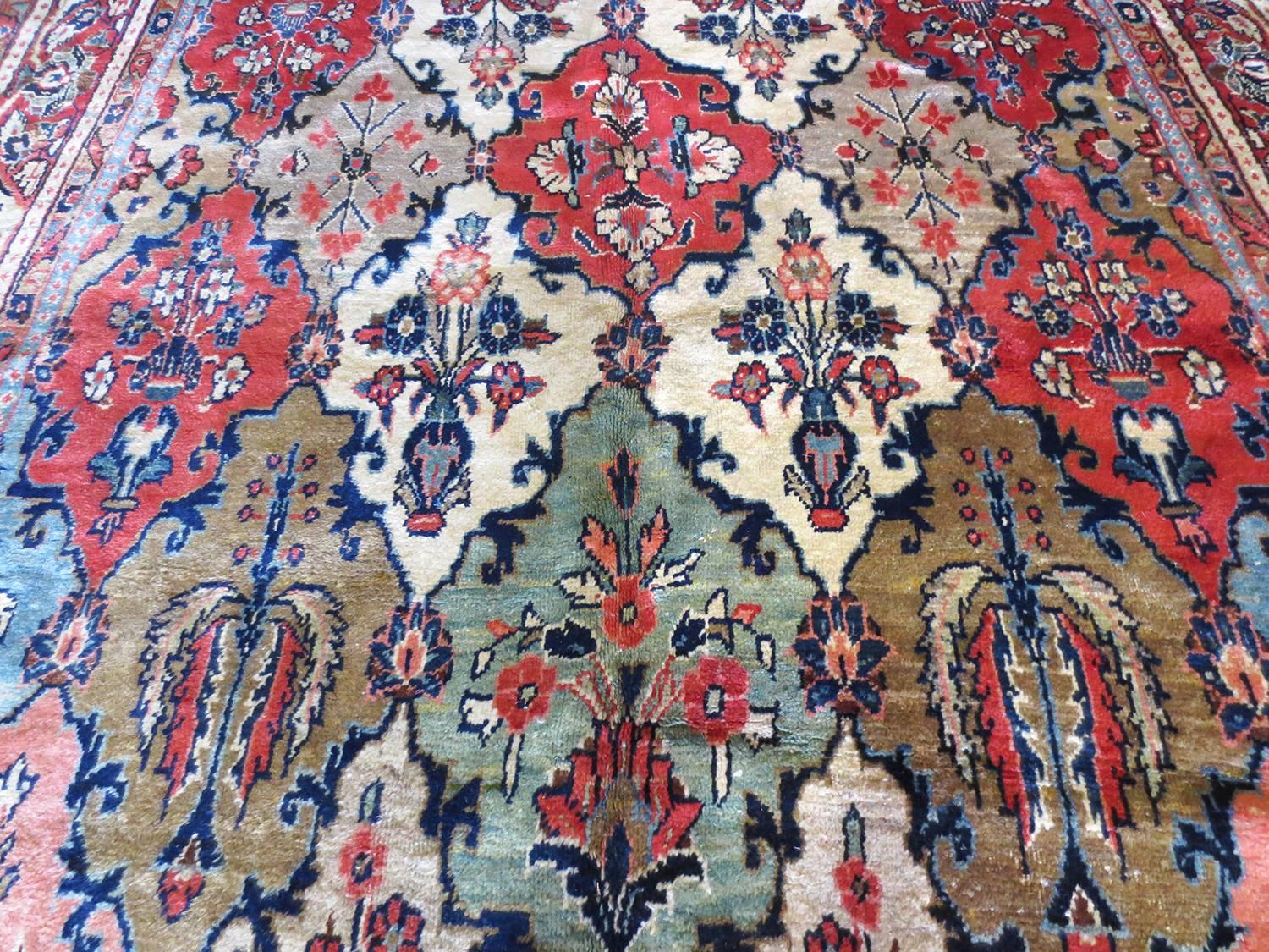 This is a vintage Bakhtari circa 1930s. It features a latticework of four-pointed figures containing beautiful floral design with rich blues, navy, ivory, salmon, yellows greens. A multitude of borders enclose the central field and is filled with