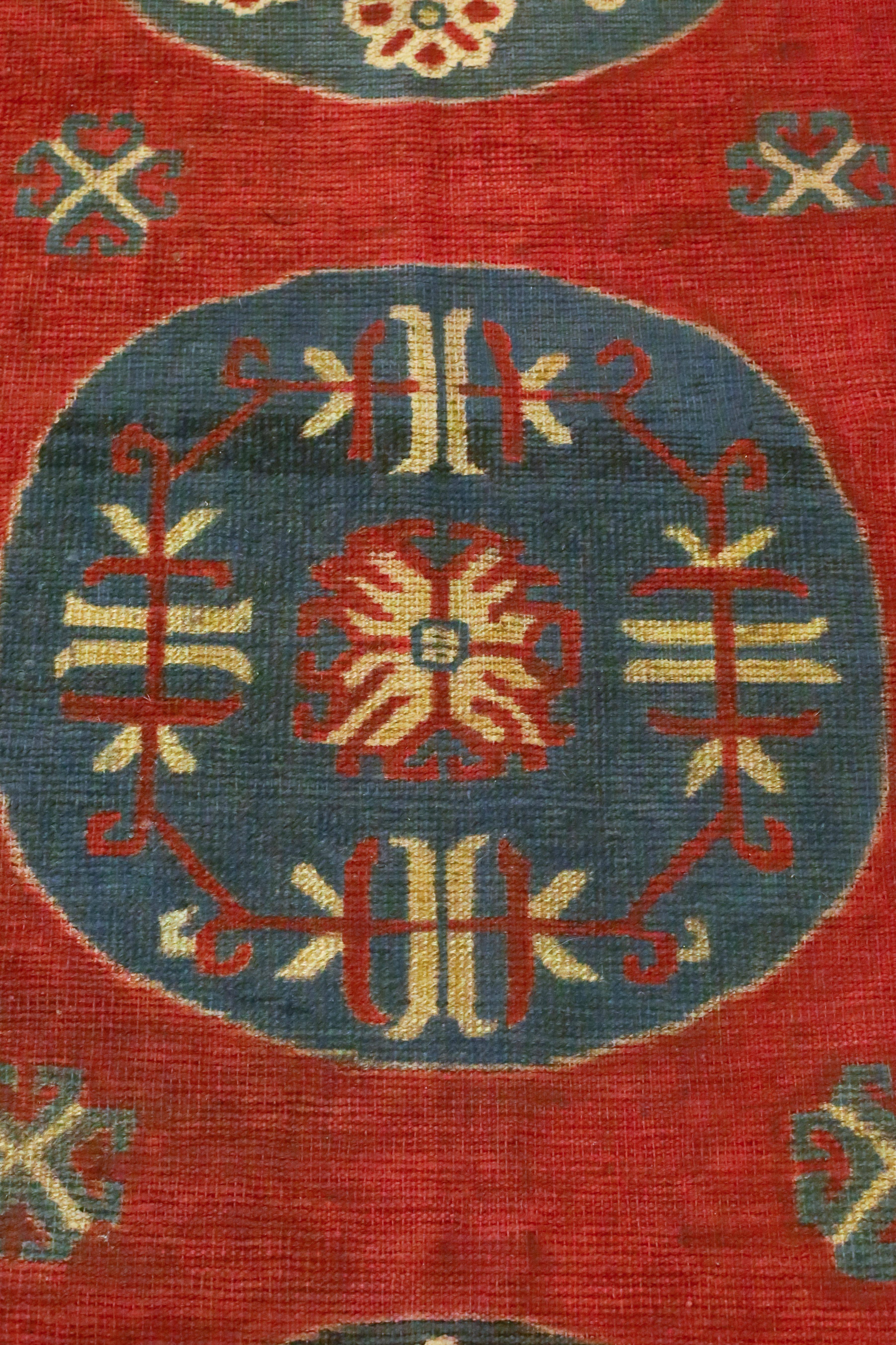 This is an antique Samarkand rug from East Turkistan, circa 1900s. Three circular medallions float on a red field that is surrounded by an infinity border and another outer border. Tones of muted reds, ivories, navys and greys, convey a feeling of