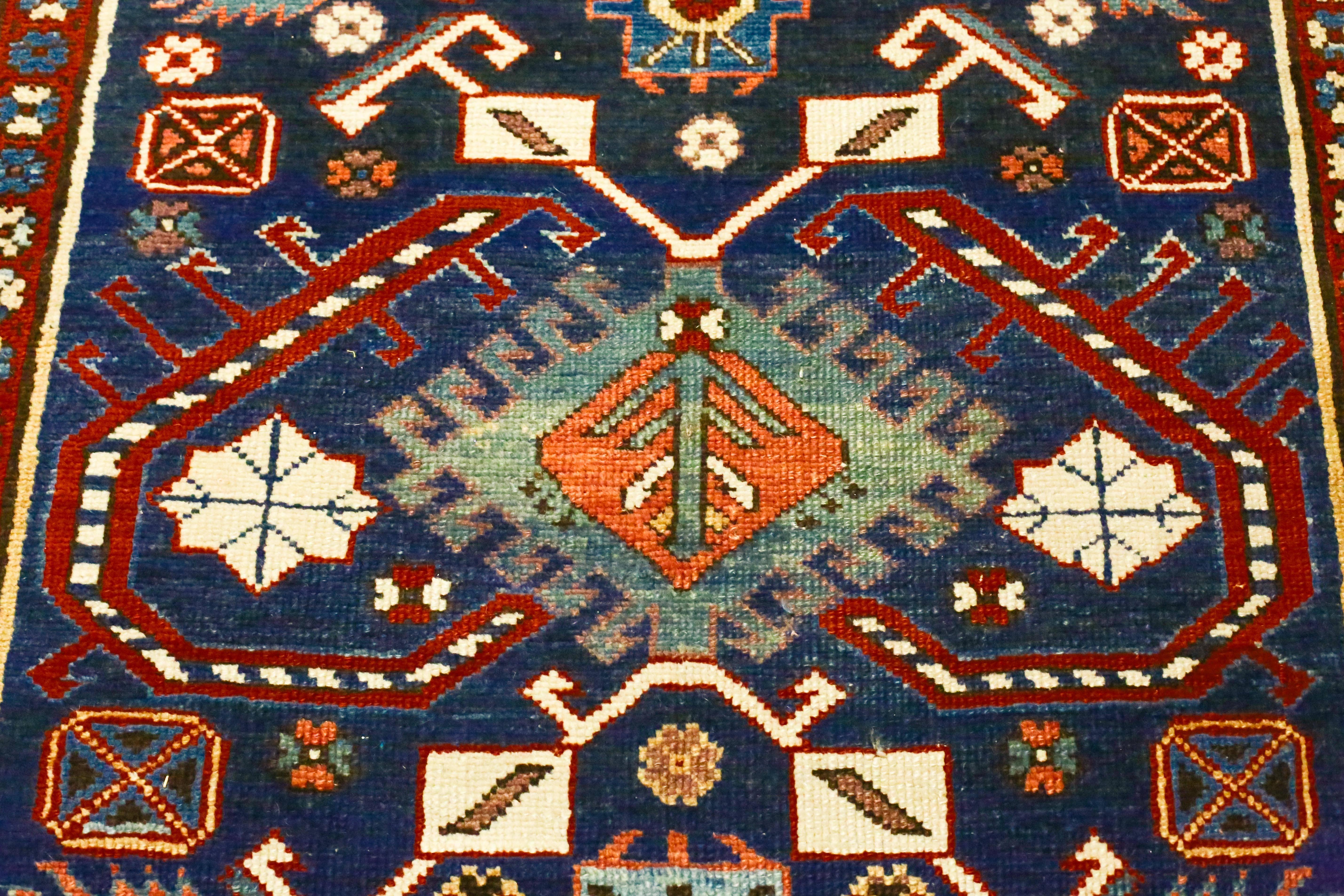 This is an antique Caucasian Kazak runner, circa 1870s. It is in mint condition with bold colors. It features bracketed medallions surrounded by a lively display of angular animals and symbols in dark navy field with accents on red, orange, ivory,