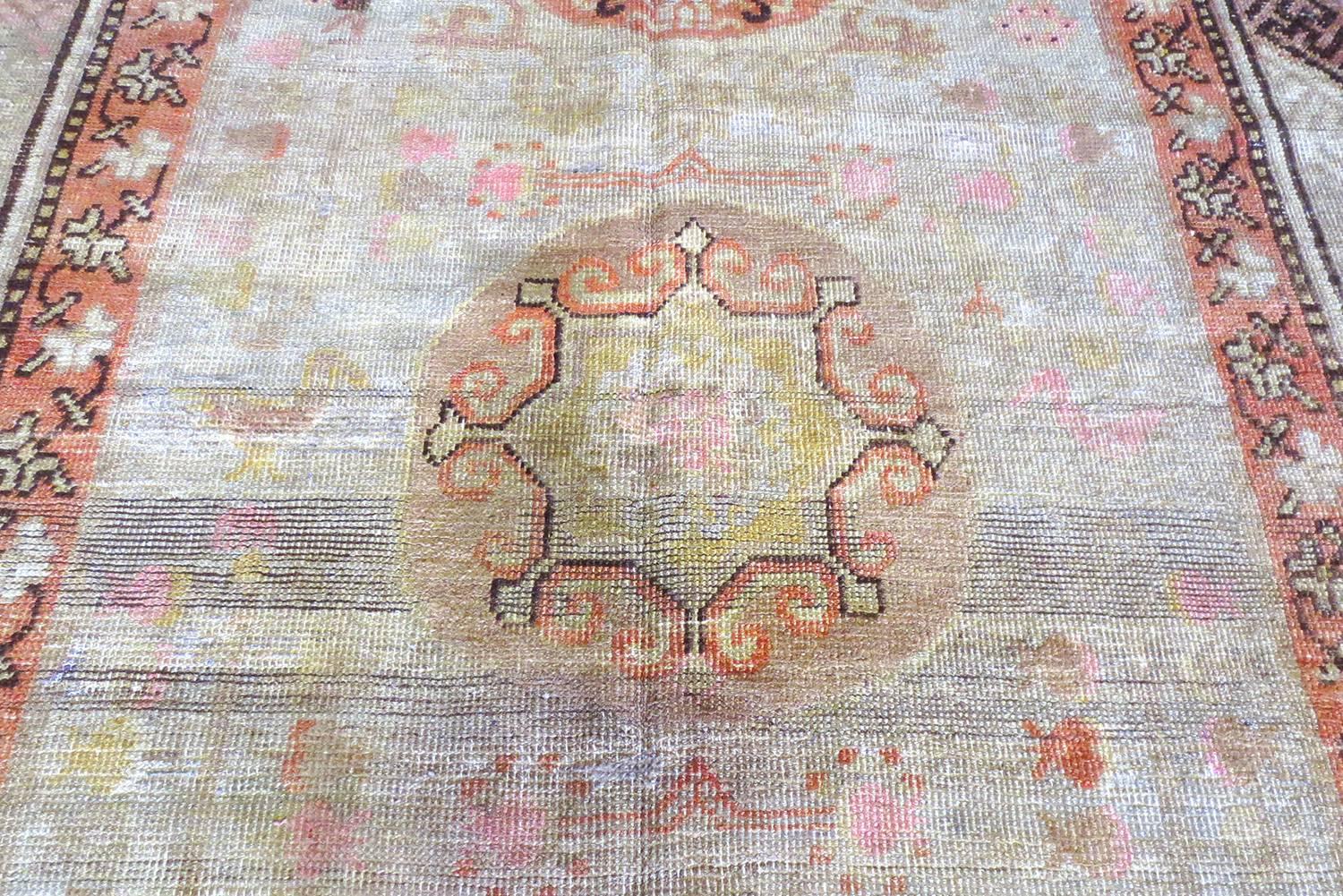 Dieser antike Khotan-Teppich aus Ostturkestan um 1860 ist ein großartiges Beispiel für die frühen Teppiche aus dieser Region mit drei schönen kreisförmigen Medaillons, jedes mit einem einzigartigen Design und Anordnung. Das graue Feld wird von
