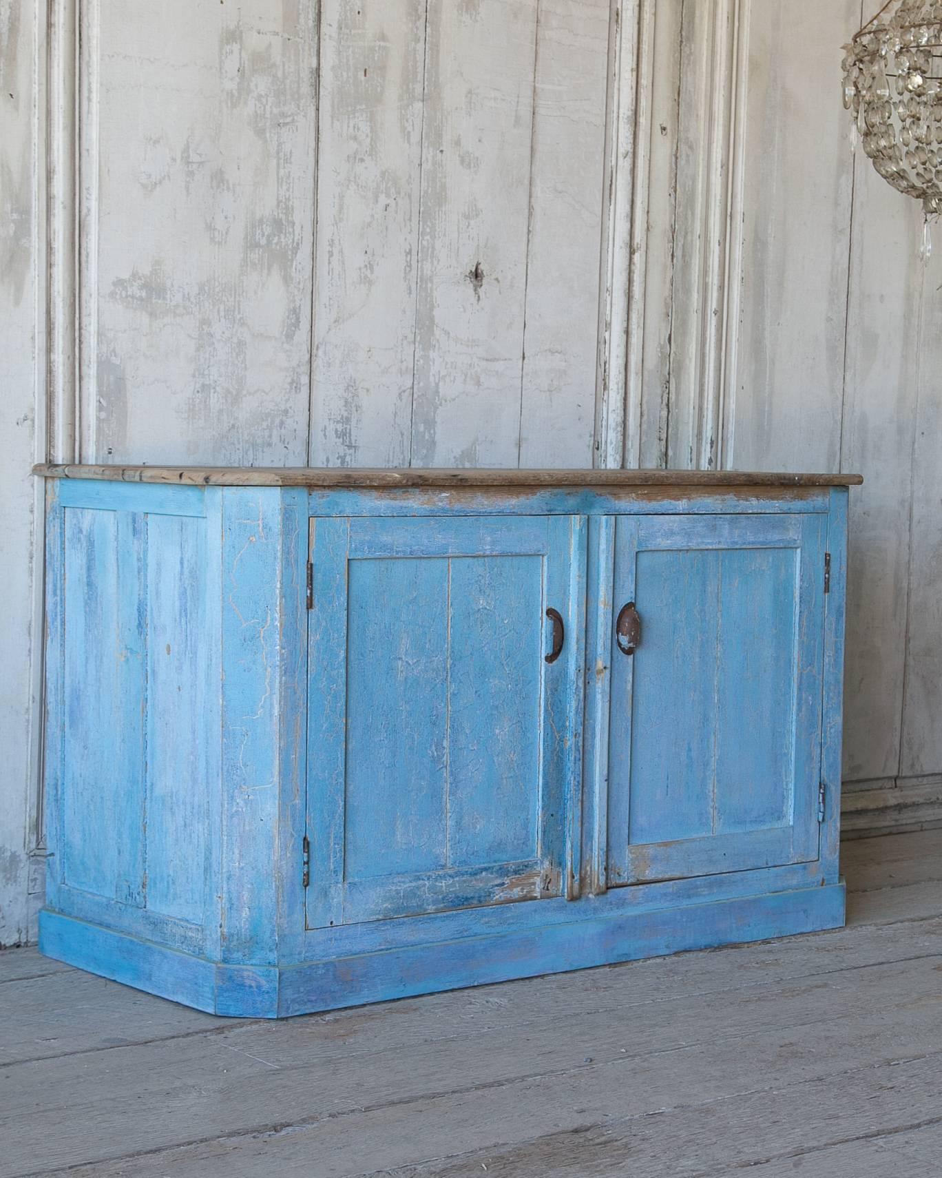 Amazing French two-door antique sideboard. Stunning aged blue painted finish. Worn wood top with fixed middle shelf. Functional hardware with a gorgeous aged patina. Adds just the right pop of color to your space!