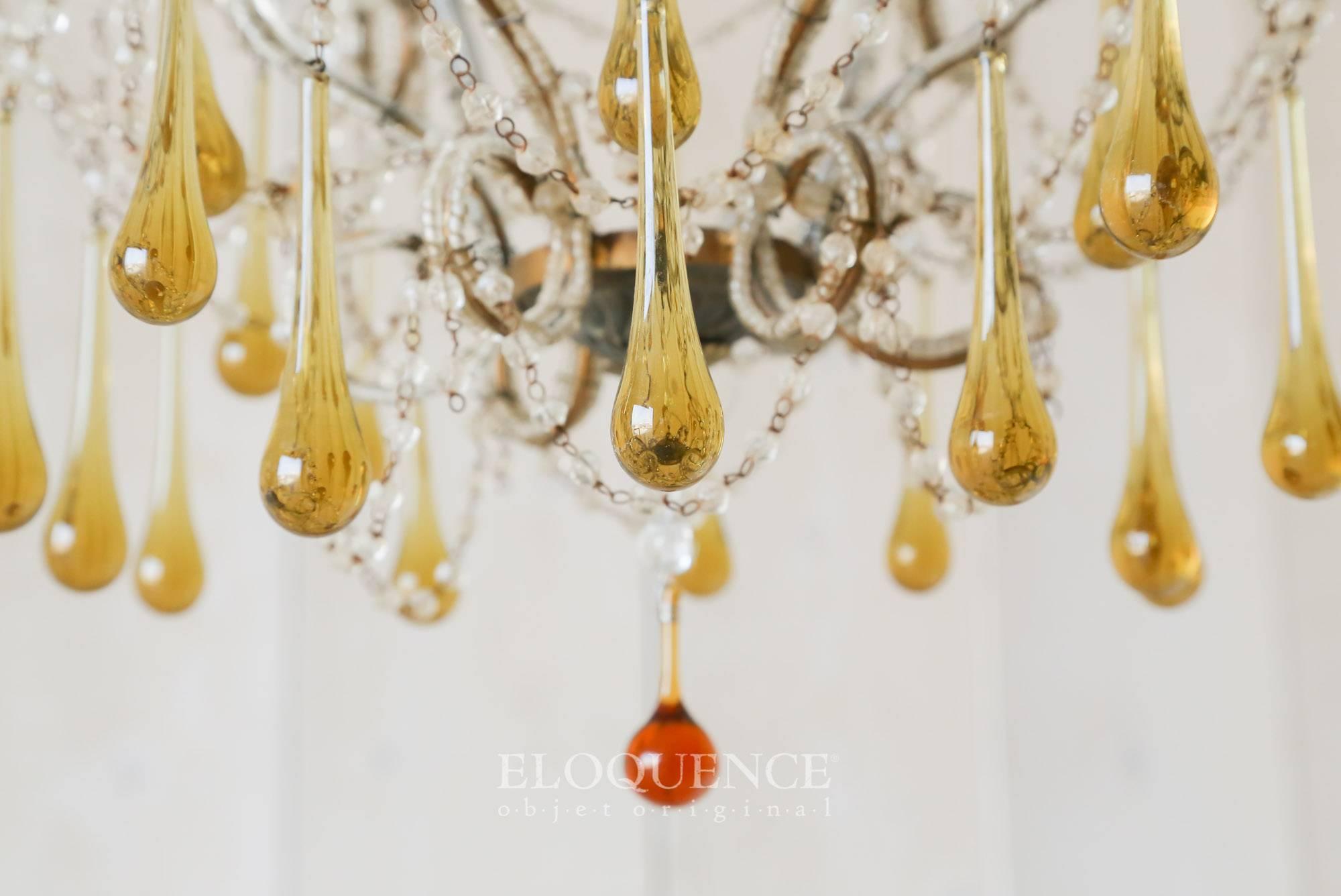 Stunning antique Italian chandelier in a deep brass. Each of the scrolling six arms are covered in glass beading and topped with glass candle cups. Strings of glass beads and pendants of honey colored pendants simply drip off the cage design. This