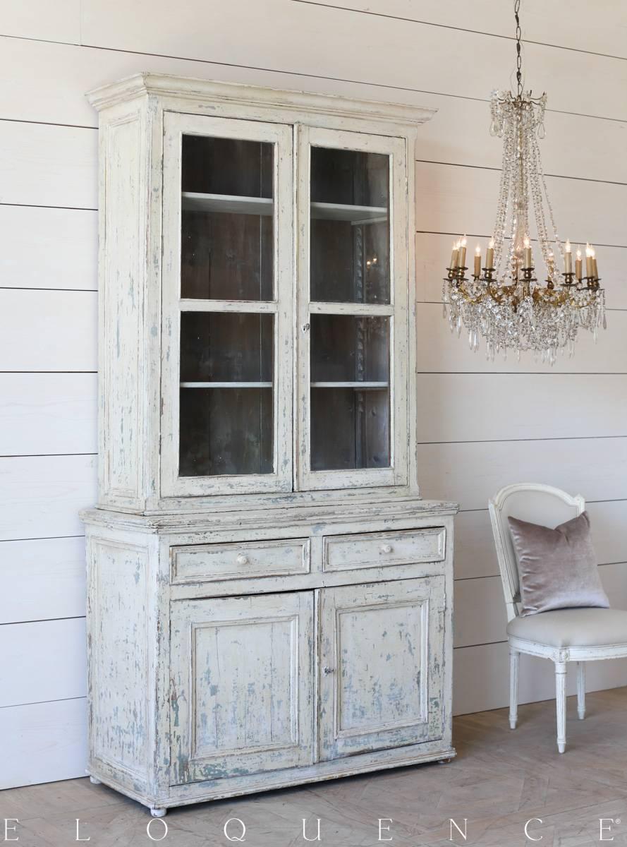 Darling antique cabinet in a heavily distressed cream finish with teal and true white accents rubbed back to a natural wood. The hutch boasts original glass doors that open to four spacious shelves. Two drawers and cabinets below provide additional